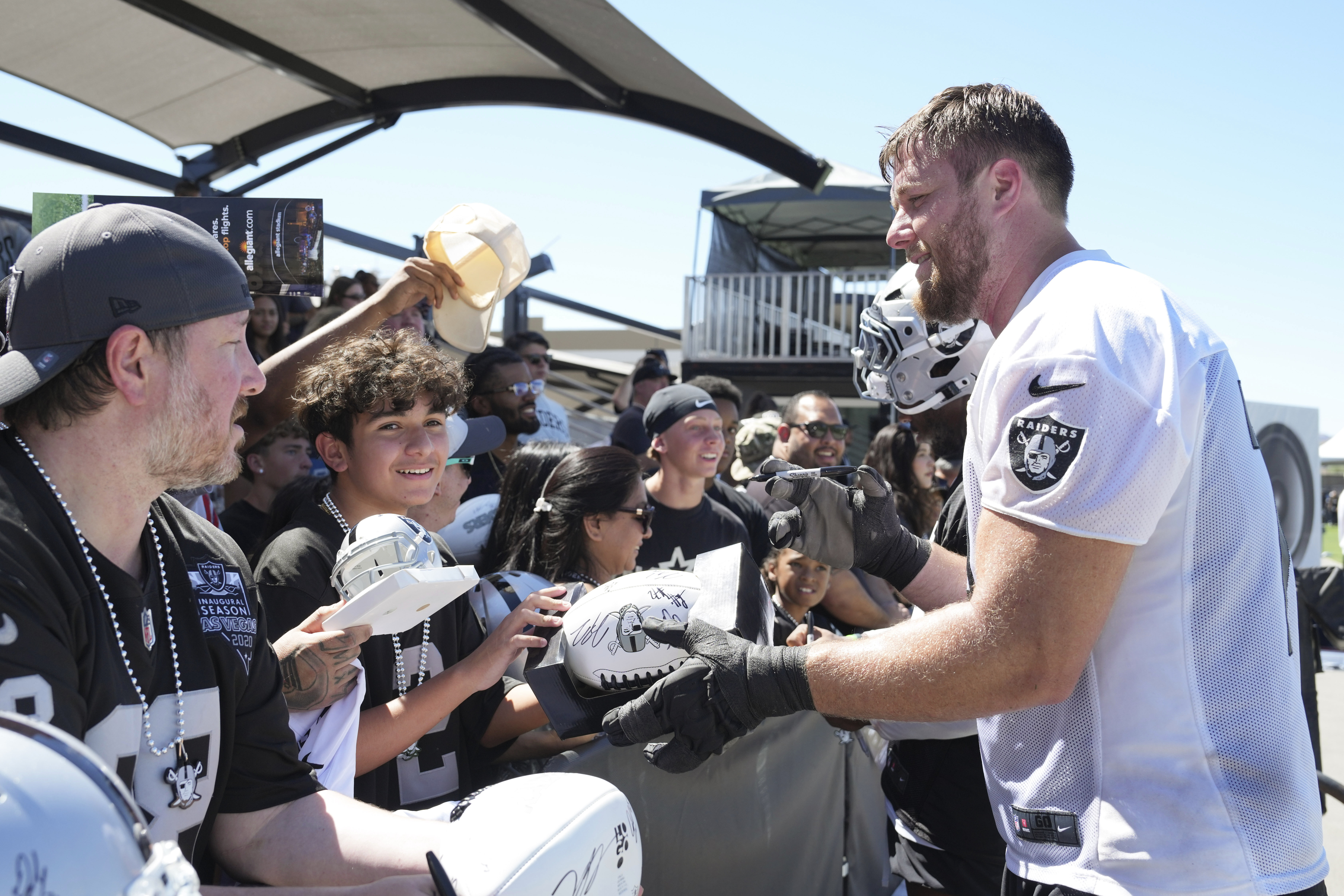 Las Vegas Raiders offensive tackle Kolton Miller, right, gives autographs after the team's NFL football training camp, Sunday, July 27, 2025, in Henderson, Nev.