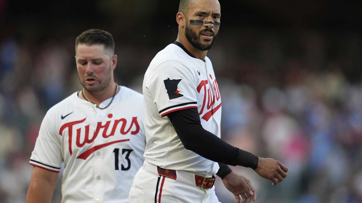 Minnesota Twins' Carlos Correa, right, walks across the field near Ty France (13) after hitting a lineout to third base to end the bottom of the third inning of a baseball game against the Washington Nationals, Saturday, July 26, 2025, in Minneapolis.