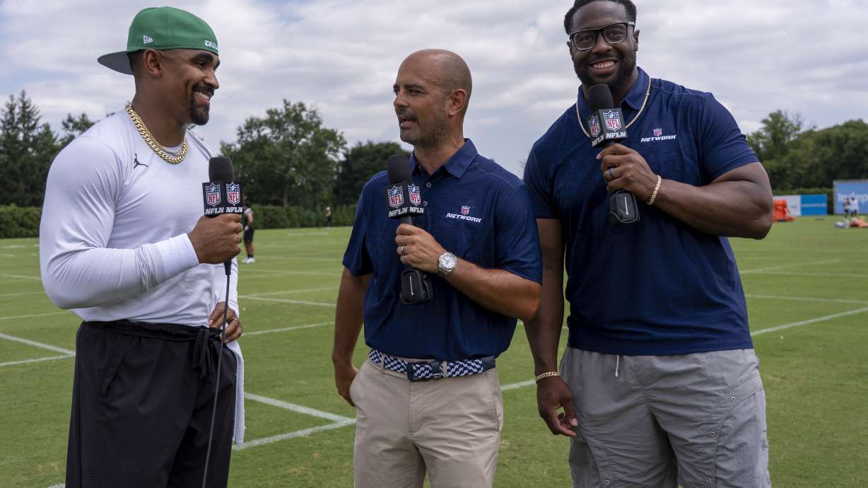 Philadelphia Eagles' Jalen Hurts, left, is interviewed by NFL Network talent Mike Garafolo, center, and Gerald McCoy, right, following practice at the team's NFL football training camp, Saturday, July 26, 2025, in Philadelphia.