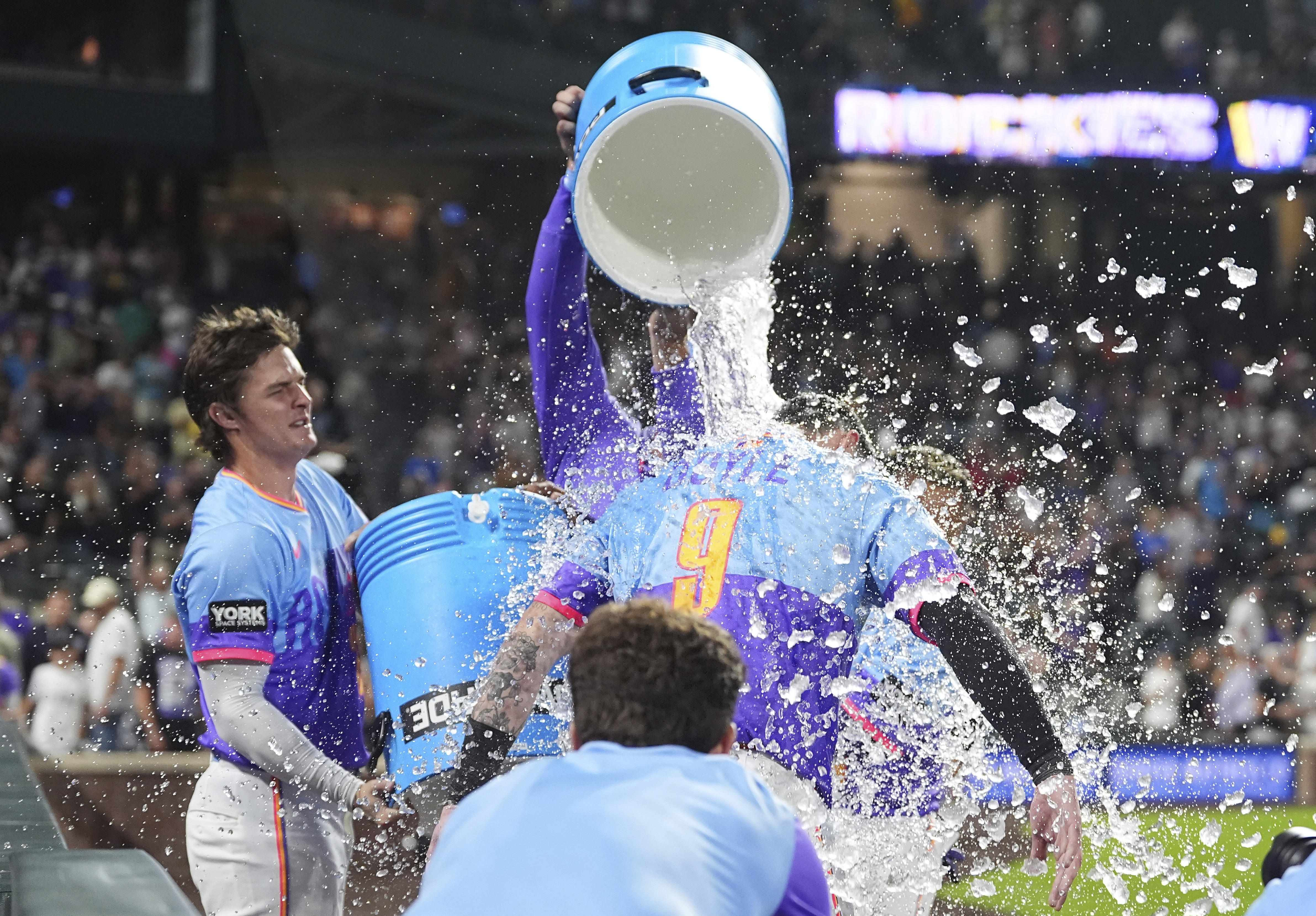 Colorado Rockies' Mickey Moniak, back left, and Orlando Arcia, back right, douse Brenton Doyle (9) after Doyle hit a two-run wakoff home run off Pittsburgh Pirates relief pitcher Dennis Santana in the ninth inning of a baseball game Friday, Aug. 1, 2025, in Denver.