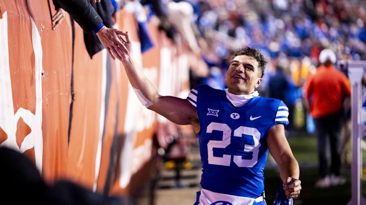 BYU running back Pokaiaua Haunga (23) high-fives fans after the Cougars defeated Utah 22-21 at Rice-Eccles Stadium in Salt Lake City early on Sunday, Nov. 10, 2024.