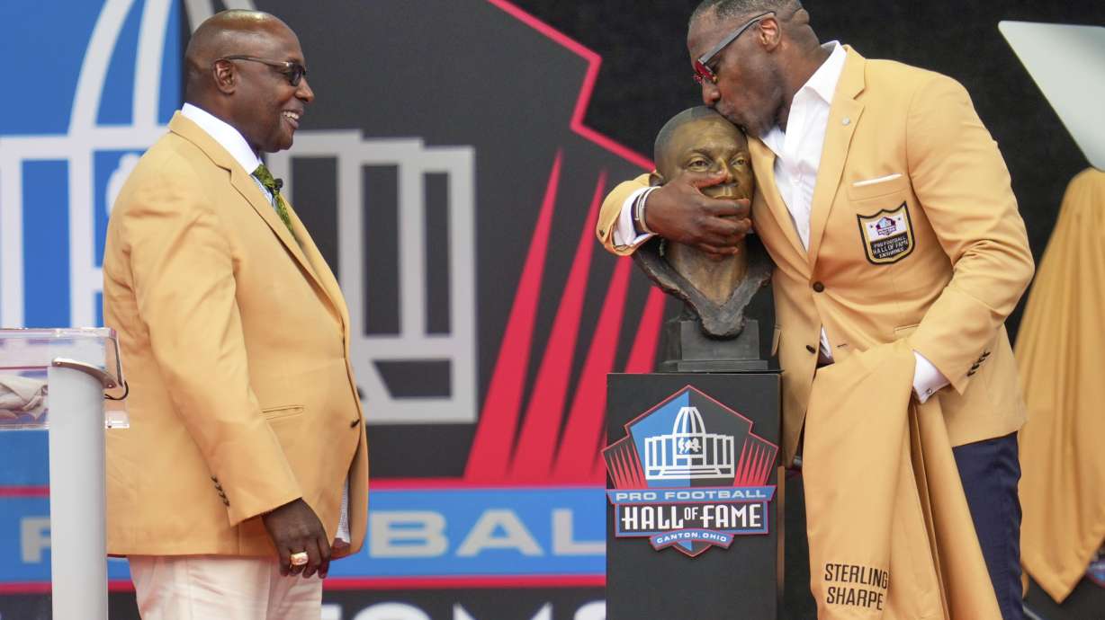 Former NFL player Sterling Sharpe, left, watches as his brother Shannon Sharpe kisses his bust during an induction ceremony at the Pro Football Hall of Fame, in Canton, Ohio, Saturday, Aug. 2, 2025, in Canton, Ohio.