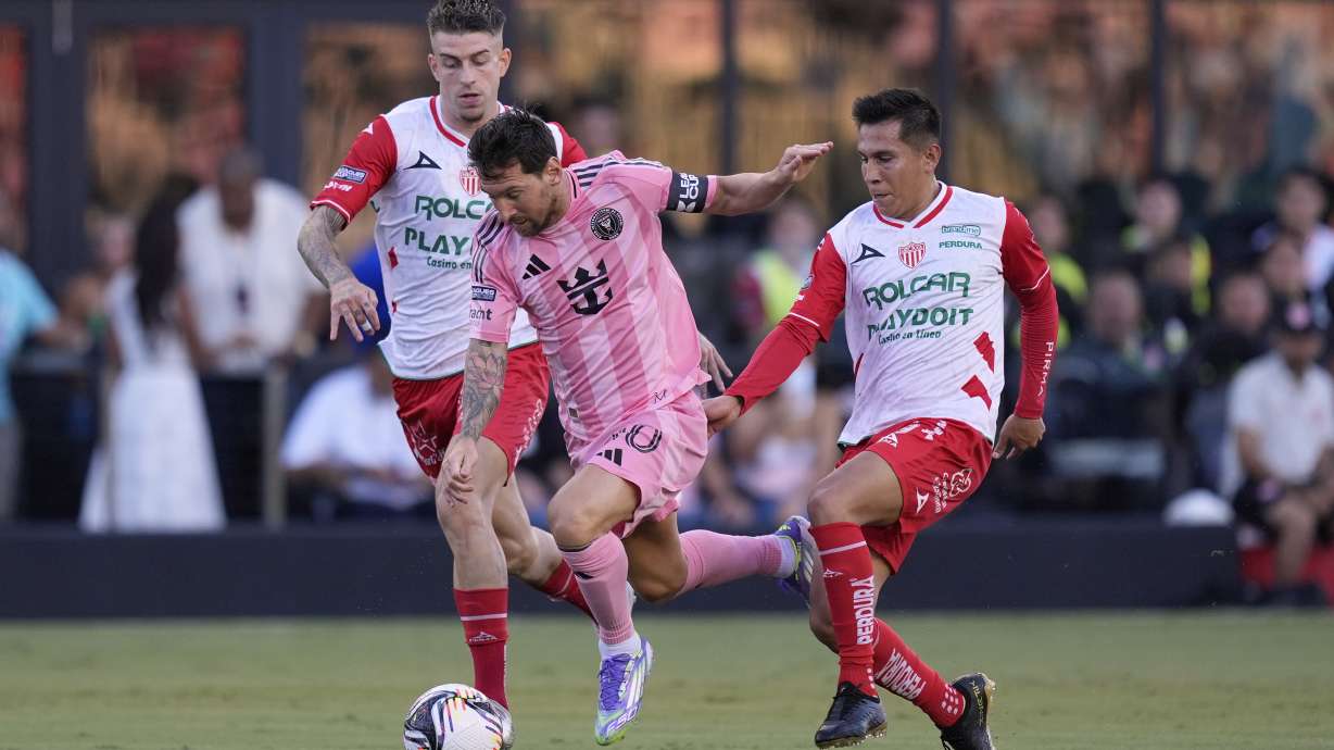 Inter Miami forward Lionel Messi, center, charges through Necaxa forward Raul Sanchez, left, and midfielder Jose Rodriguez, during the first half of a Leagues Cup soccer match, Saturday, Aug. 2, 2025, in Fort Lauderdale, Fla.