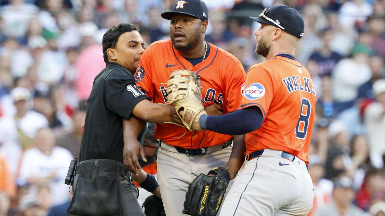 Home plate umpire Gerry Davis, left, and Houston Astros first baseman Christian Walker (8) restrain Astros pitcher Hector Neris, center, at the end of the seventh inning of a baseball game against the Boston Red Sox, Saturday, Aug. 2, 2025, in Boston.