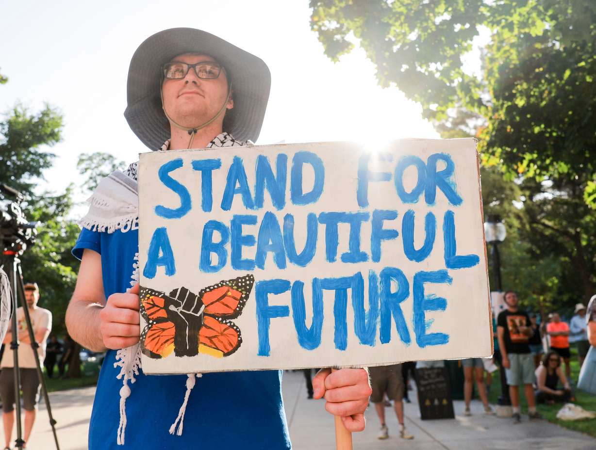 Jason Hutchinson holds a sign during a Rage Against the Regime rally at Washington Square in Salt Lake City on Saturday.