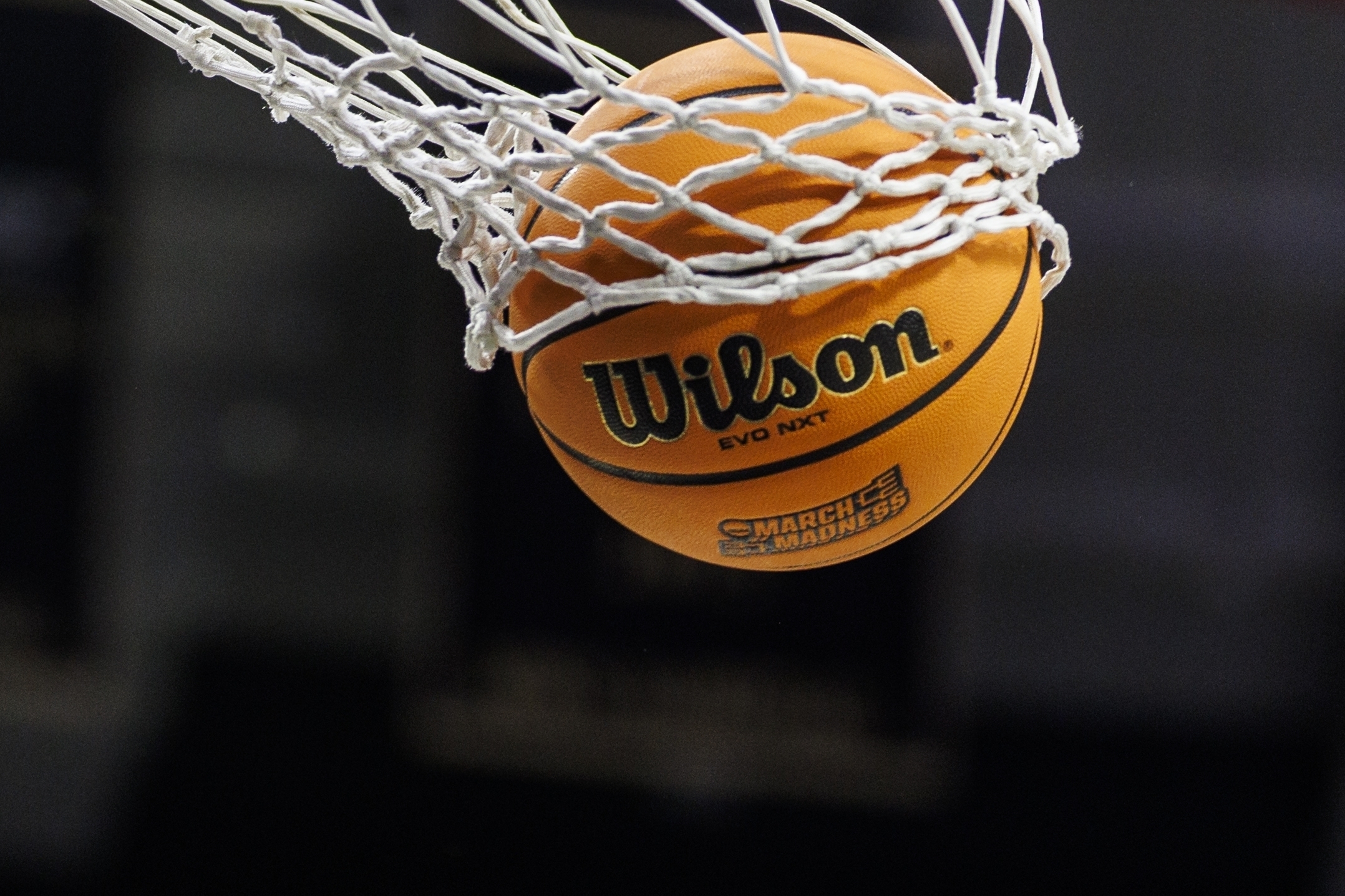 FILE - A basketball with a March Madness logo is seen going through a net prior to a second round of the NCAA college basketball tournament between Notre Dame and Michigan, March 23, 2025, in South Bend, Ind.