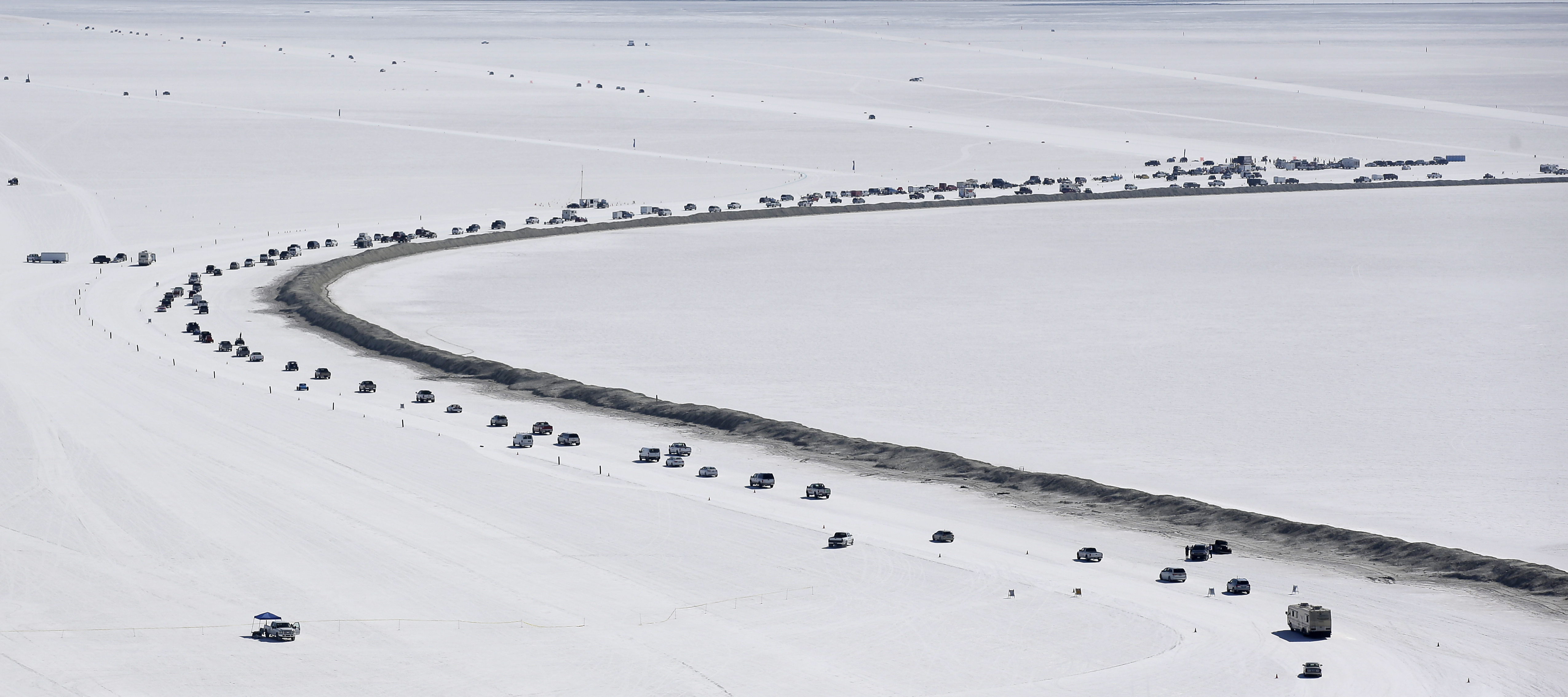 FILE - Cars form a line near the race track at the Bonneville Salt Flats near Wendover, Utah, Aug. 13, 2016.