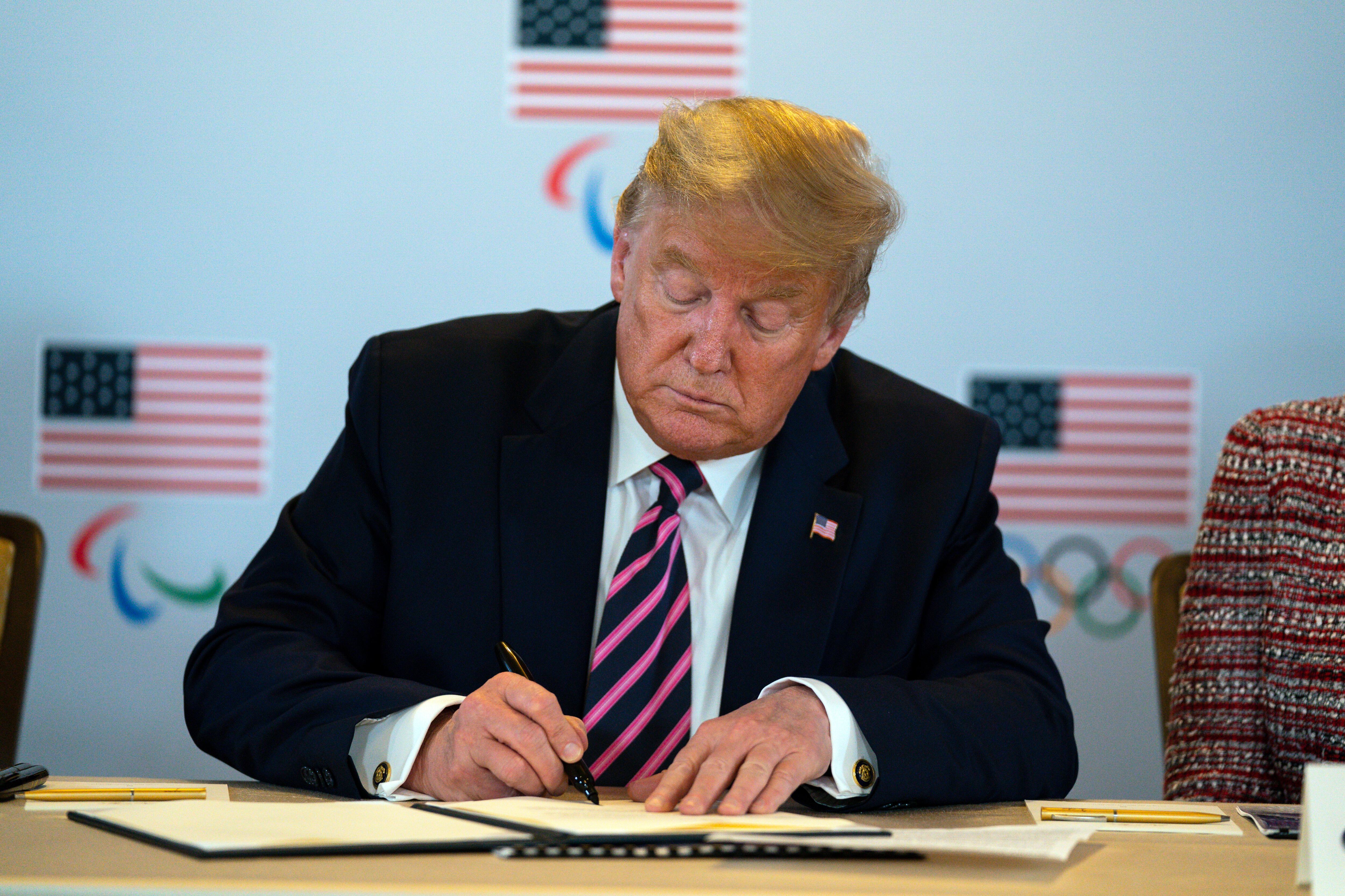 President Donald Trump signs a document during a meeting with U.S. Olympic officials and Los Angeles 2028 organizers, Feb. 18, 2020, in Beverly Hills, Calif. Trump signed an executive order Tuesday creating a task force for the 2028 Summer Games.