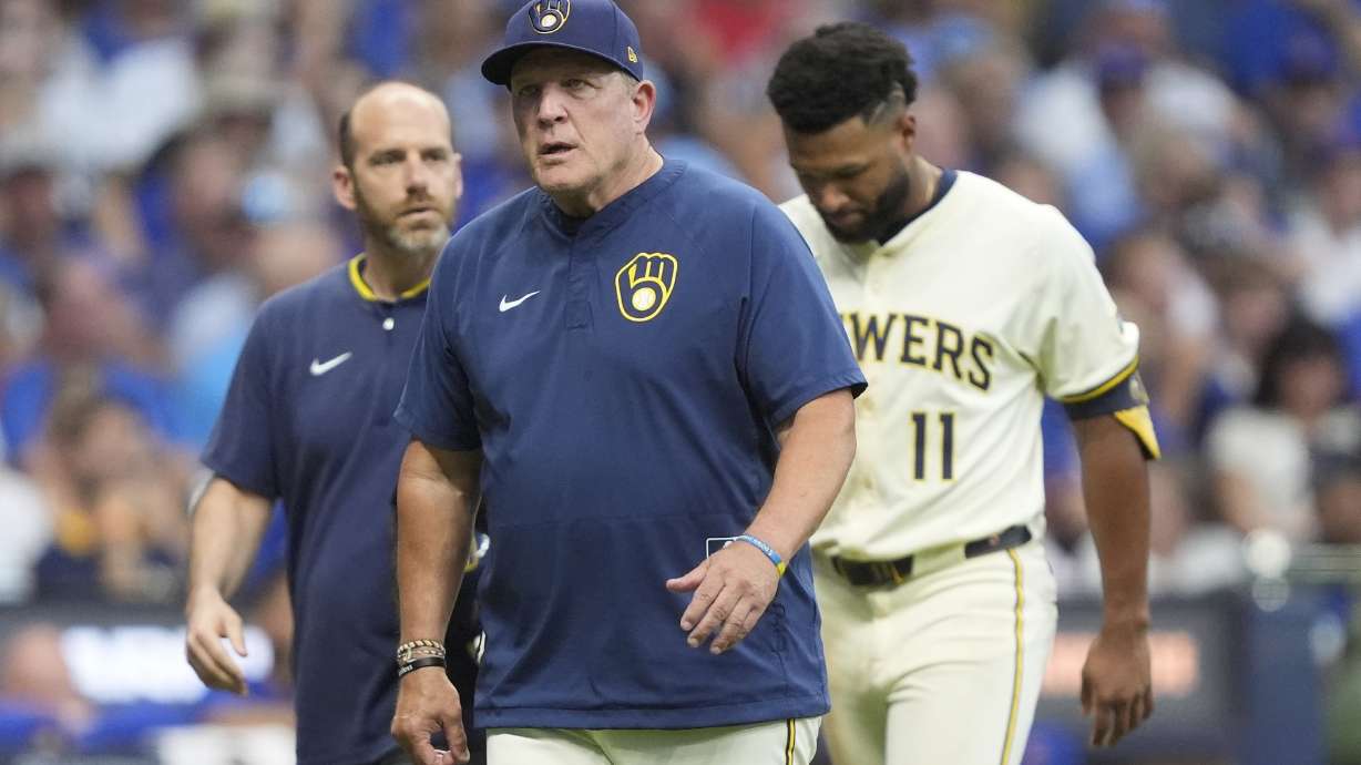 Milwaukee Brewers manager Pat Murphy, middle, walks to the dugout with Jackson Chourio (11) during the fifth inning of a baseball game against the Chicago Cubs, Tuesday, July 29, 2025, in Milwaukee. Chourio was removed from the game after suffering an injury.
