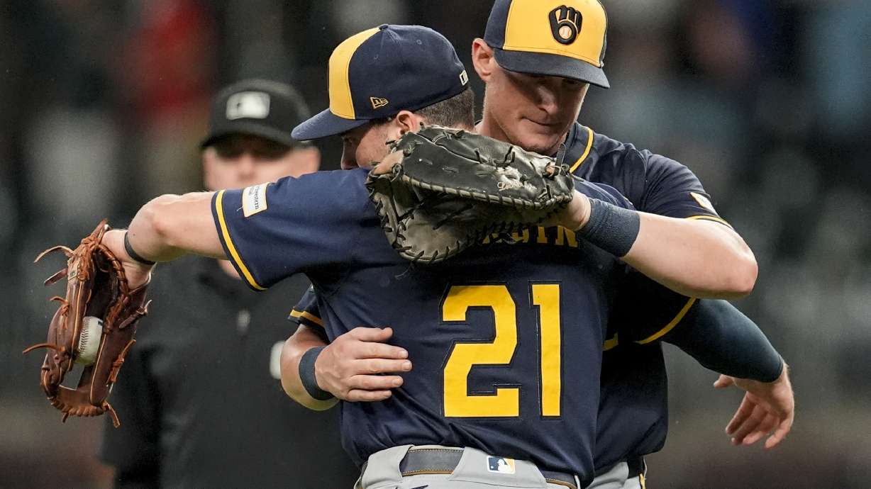 Milwaukee Brewers' Caleb Durbin (21) embraces Andrew Vaughn (28) after a baseball game against the Atlanta Braves, Tuesday, Aug. 5, 2025, in Atlanta.