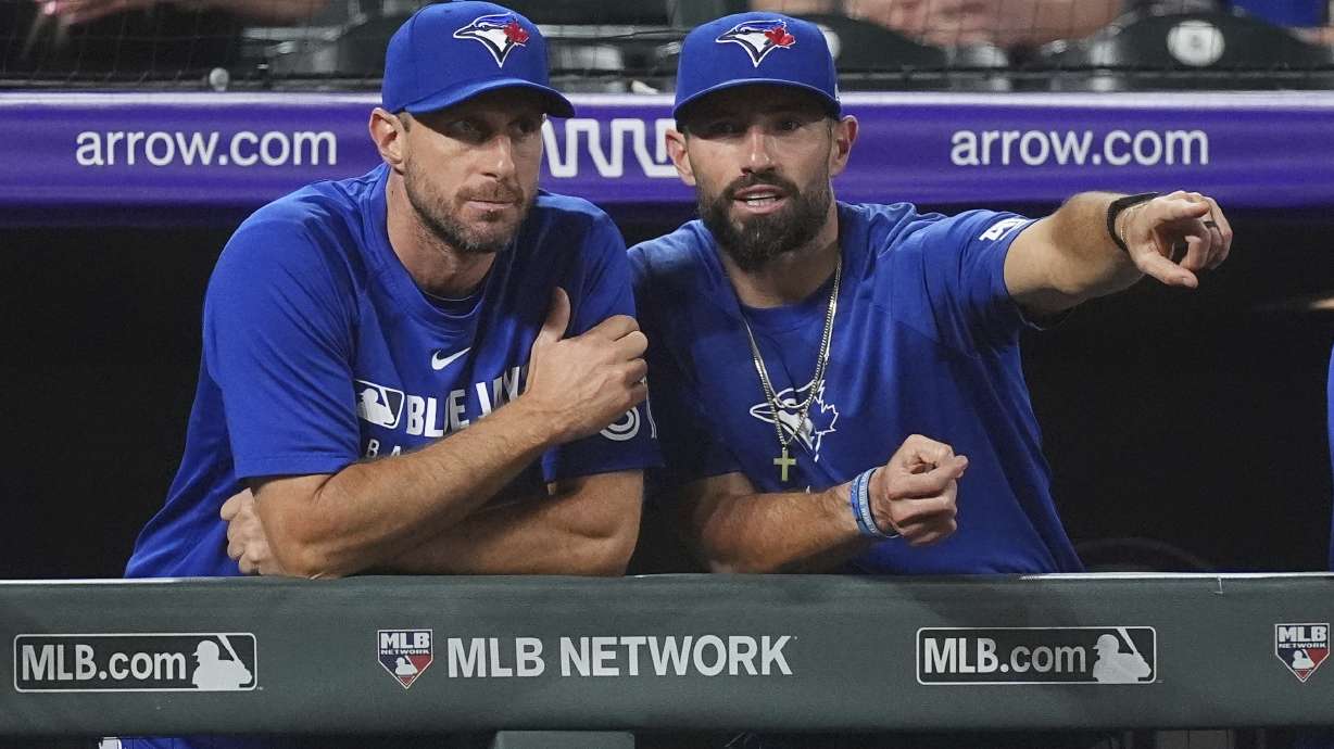 Toronto Blue Jays pitcher Max Scherzer, left,talks with assistant hitting coach Hunter Mense as they look on in the ninth inning of a baseball game against the Colorado Rockies, Monday, Aug. 4, 2025, in Denver.