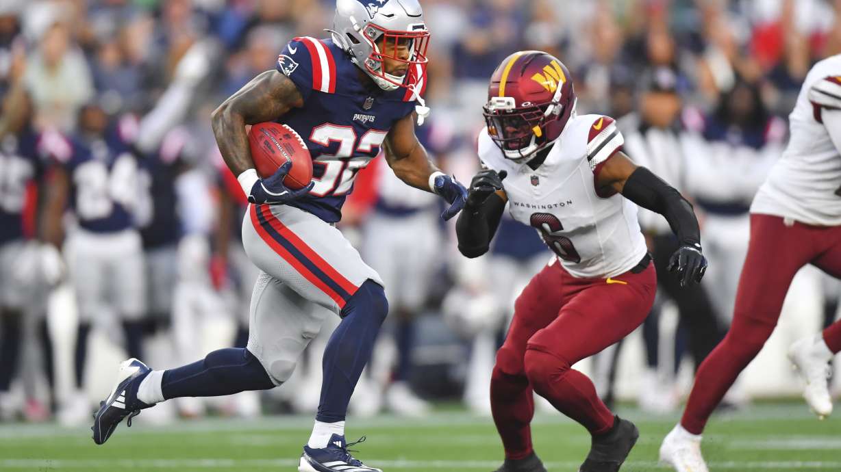 New England Patriots running back TreVeyon Henderson (32) runs the ball back for a touchdown against Washington Commanders cornerback Noah Igbinoghene (6) during the first half of an NFL preseason football game Friday, Aug. 8, 2025, in Foxborough, Mass.