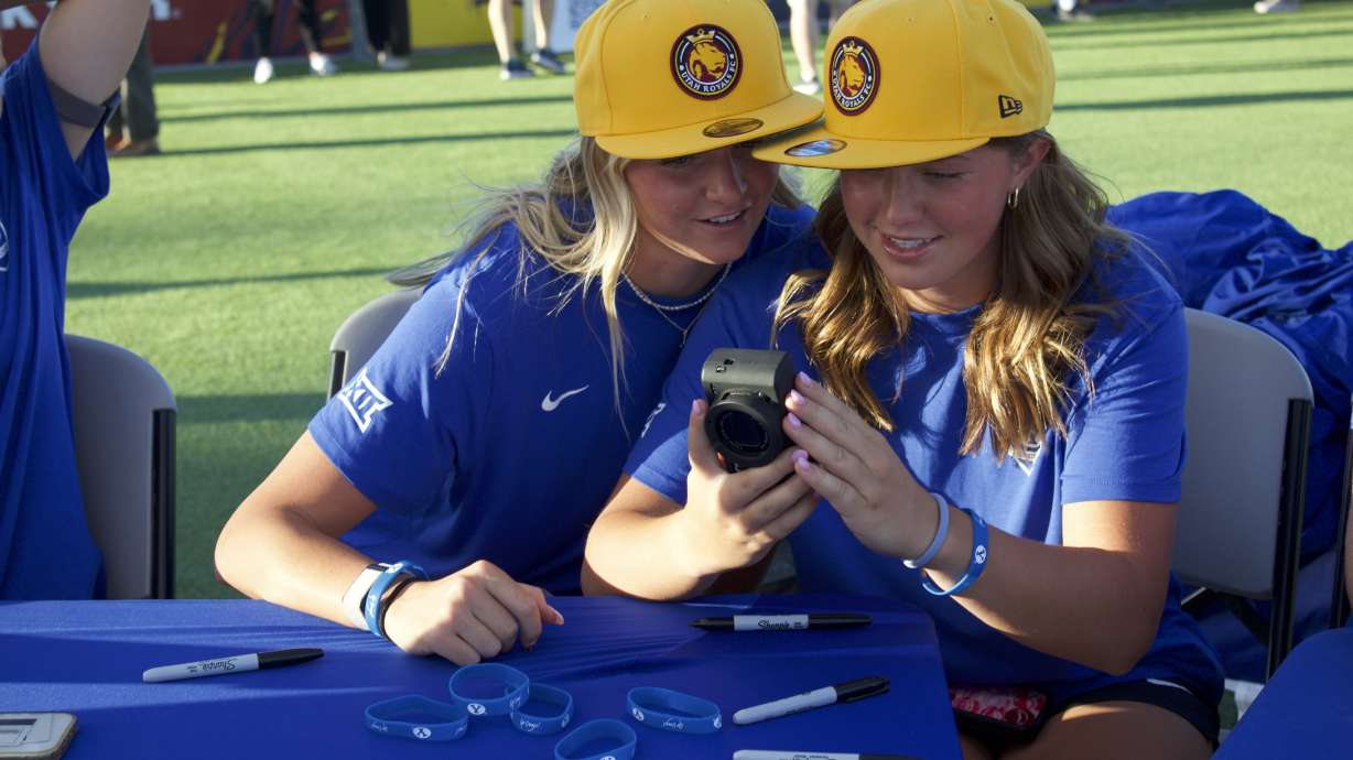 BYU women's soccer teammates Ellie Walbruch, left, and Lucy Kesler laugh at a photo on Kesler's digital camera before a Utah Royals game, Friday, Aug. 8, 2025 in Sandy, Utah.