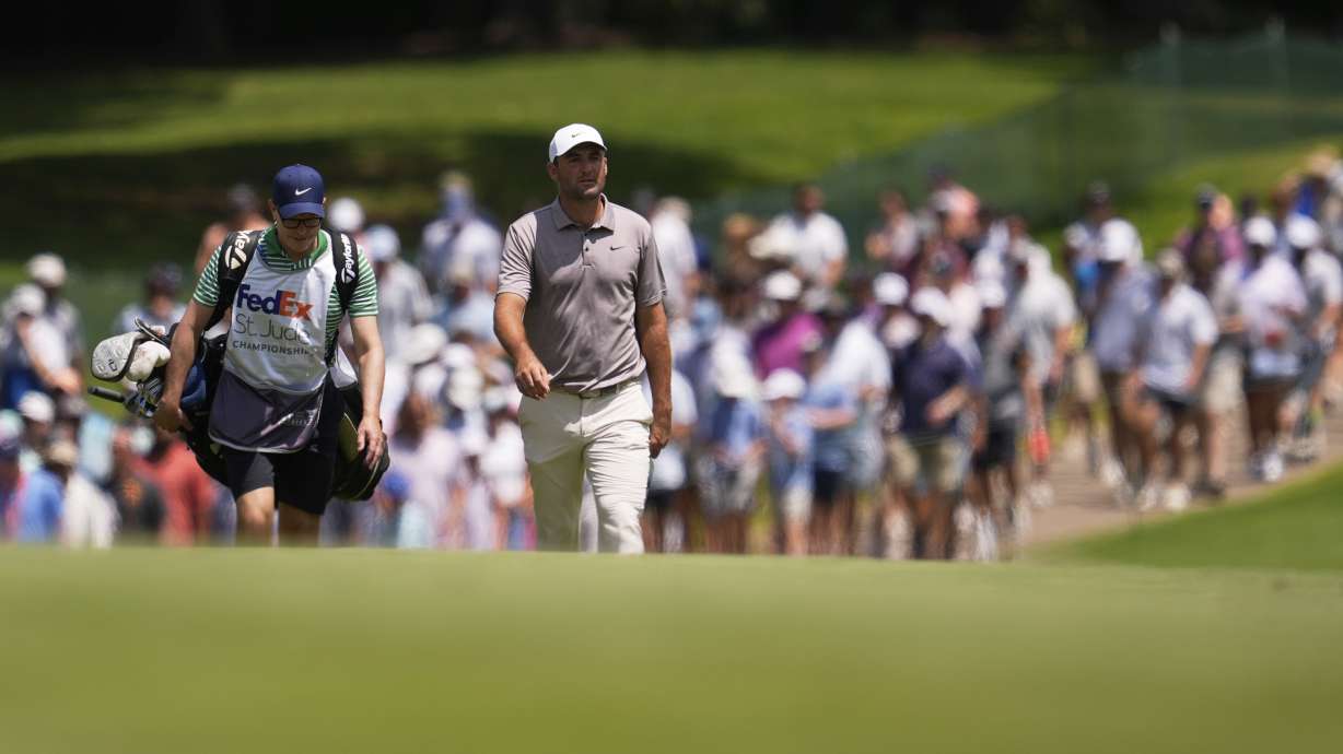 Scottie Scheffler and his caddie walk on the first fairway during the final round of the St. Jude Championship golf tournament Sunday, Aug. 10, 2025, in Memphis, Tenn.