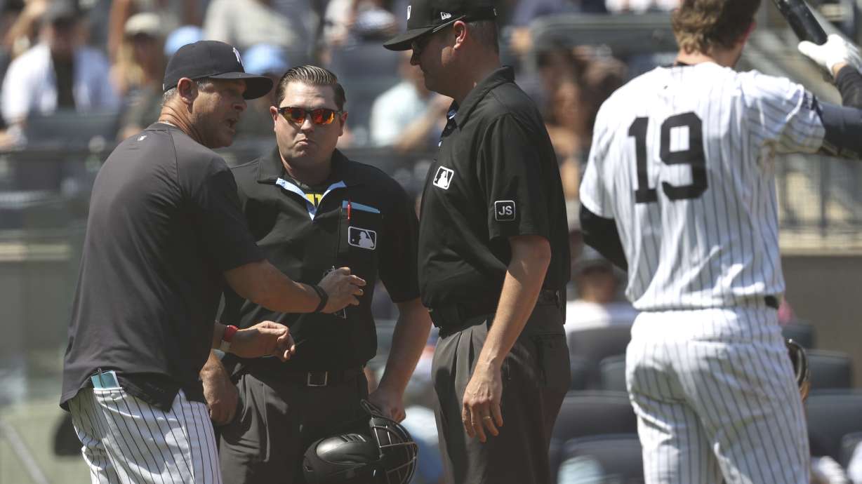 New York Yankees manager Aaron Boone, left, argues with umpires during the third inning of a baseball game against the Houston Astros, Sunday, Aug. 10, 2025, in New York.
