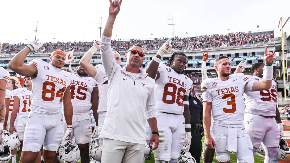 FILE - Texas tight end Jordan Washington (84), coach Steve Sarkisian, defensive back Barryn Sorrell (88) and quarterback Quinn Ewers (3) celebrate with their team after defeating Arkansas in an NCAA college football game Saturday, Nov. 16, 2024, in Fayetteville, Ark.