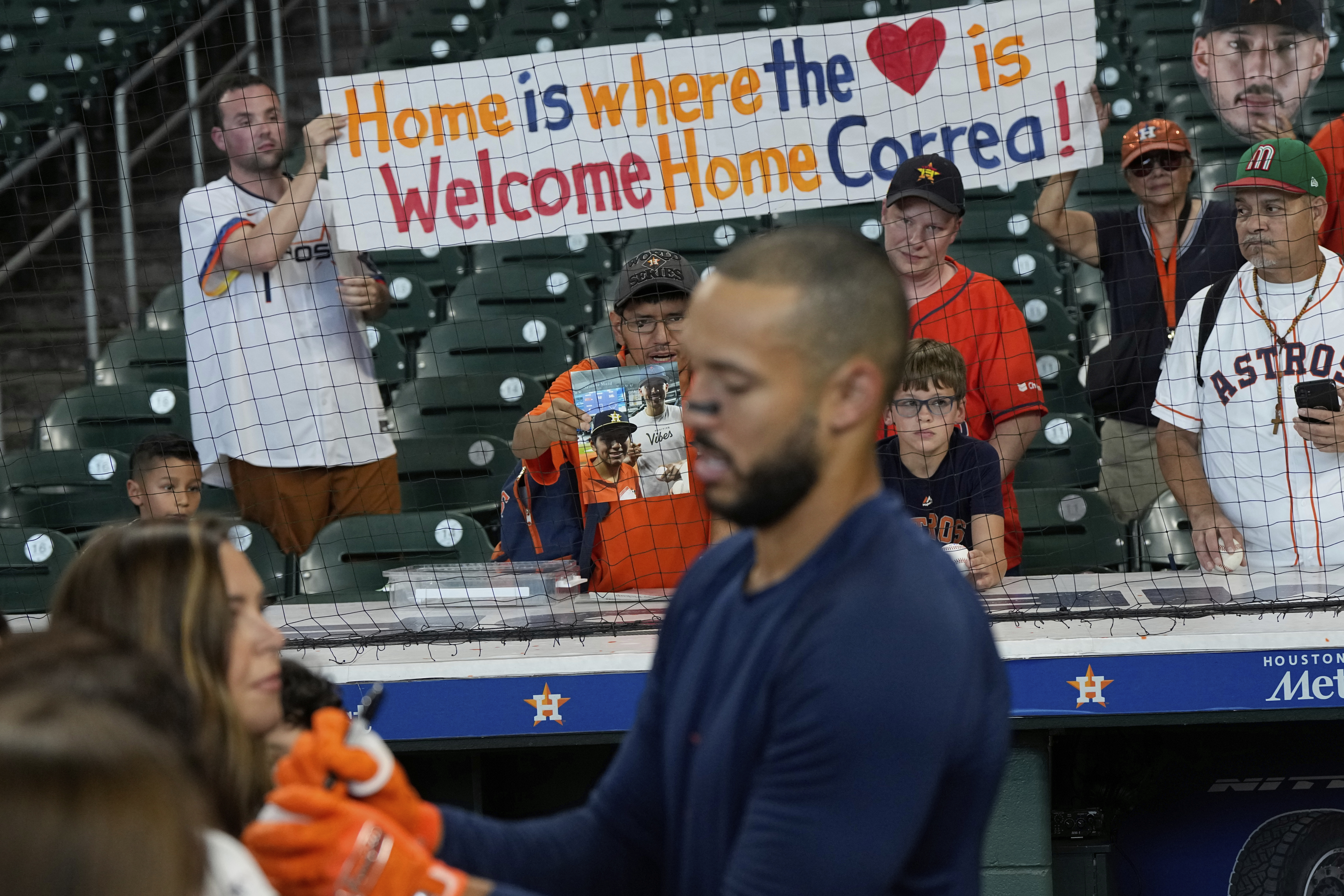 Fans hold a sign as Houston Astros third baseman Carlos Correa signs autographs during batting practice before a baseball game against the Boston Red Sox Monday, Aug. 11, 2025, in Houston.