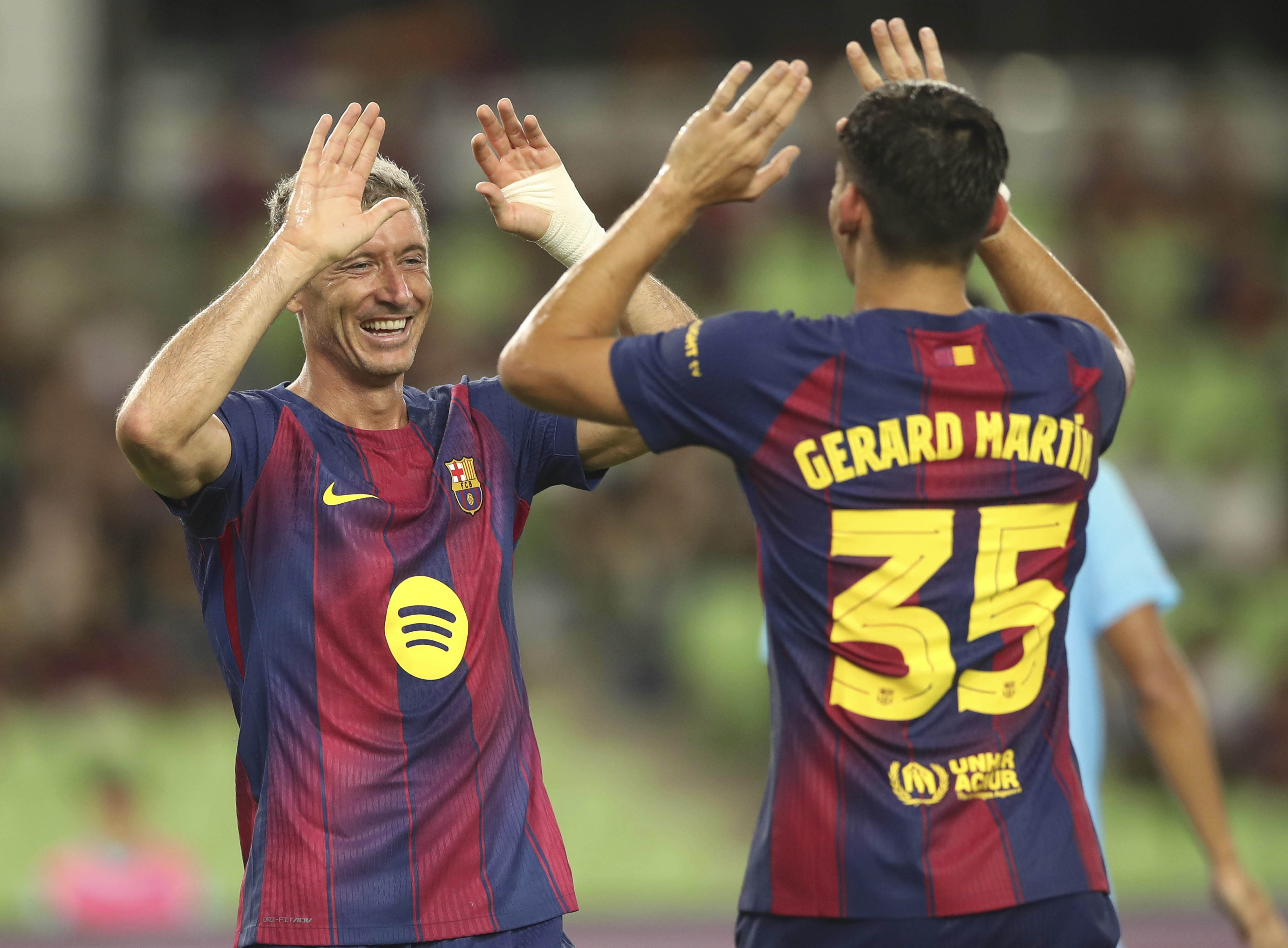 FC Barcelona's Robert Lewandowski, left, celebrates with his teammate Gerard Martin after scoring a goal during a friendly soccer match between FC Barcelona and Daegu FC at the Daegu Stadium in Daegu, South Korea, Monday, Aug. 4, 2025.