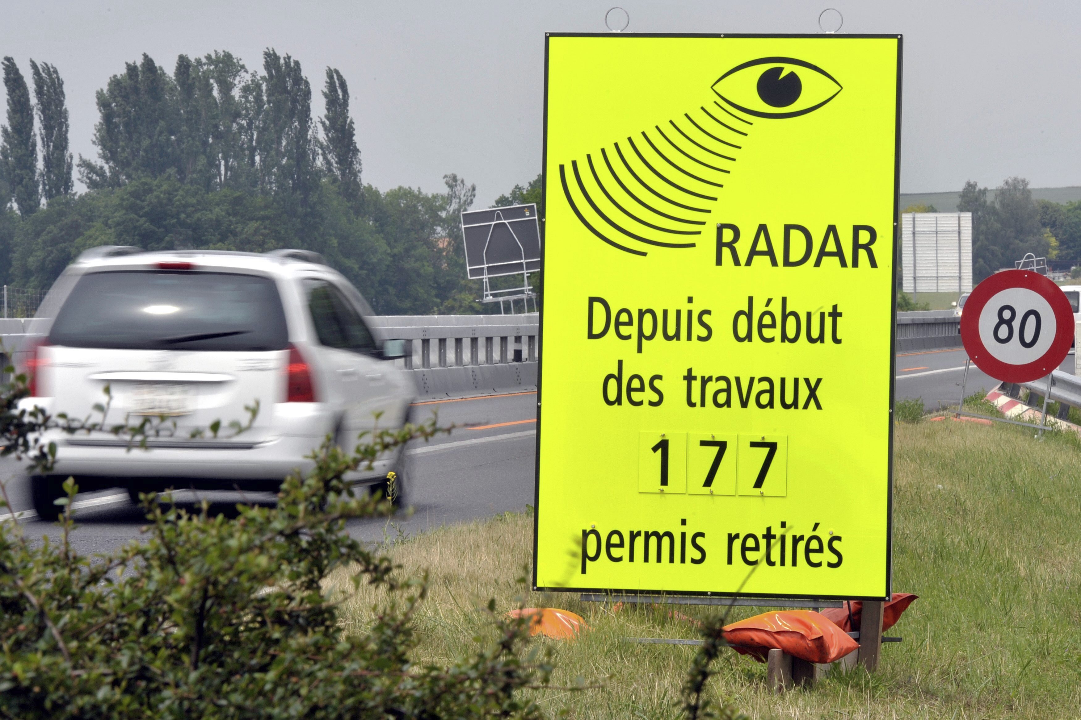A vehicle passes in front of a sign of the Vaud Cantonal Police indicating the number of driving licences withdrawn for speeding in the construction zone on the A1 motorway between Lausanne and Yverdon, Switzerland, June 15, 2010.
