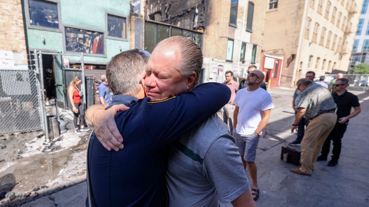 Salt Lake Fire Division Chief Bob Silverthorne hugs Jason LeCates, co-owner of Whiskey Street and White Horse, after retrieving an American flag that survived a fire that destroyed both businesses in downtown Salt Lake City on Tuesday.