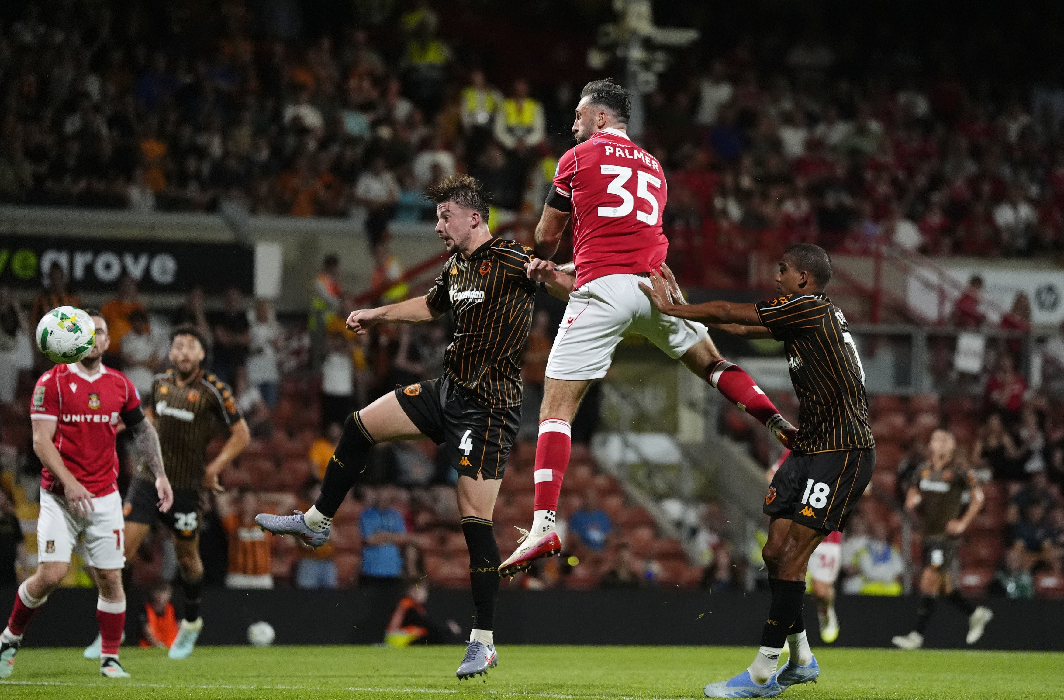 Wrexham's Ollie Palmer, top, scores during the English League Cup first round soccer match between Wrexham and Hull City at SToK Racecourse, Wrexham, Wales, Tuesday Aug. 12, 2025.