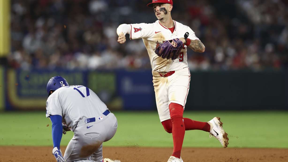 Los Angeles Angels shortstop Zach Neto (9) throws to first base to complete a double play as Los Angeles Dodgers designated hitter Shohei Ohtani (17) slides into second base during the sixth inning of a baseball game, Monday, Aug. 11, 2025, in Anaheim, Calif.