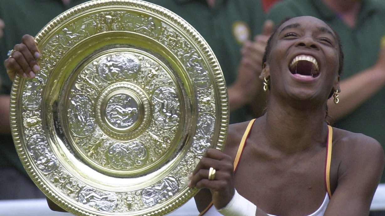 FILE - Venus Williams laughs as she holds the Women's Singles trophy on the Centre Court at Wimbledon Saturday, July 8, 2000.