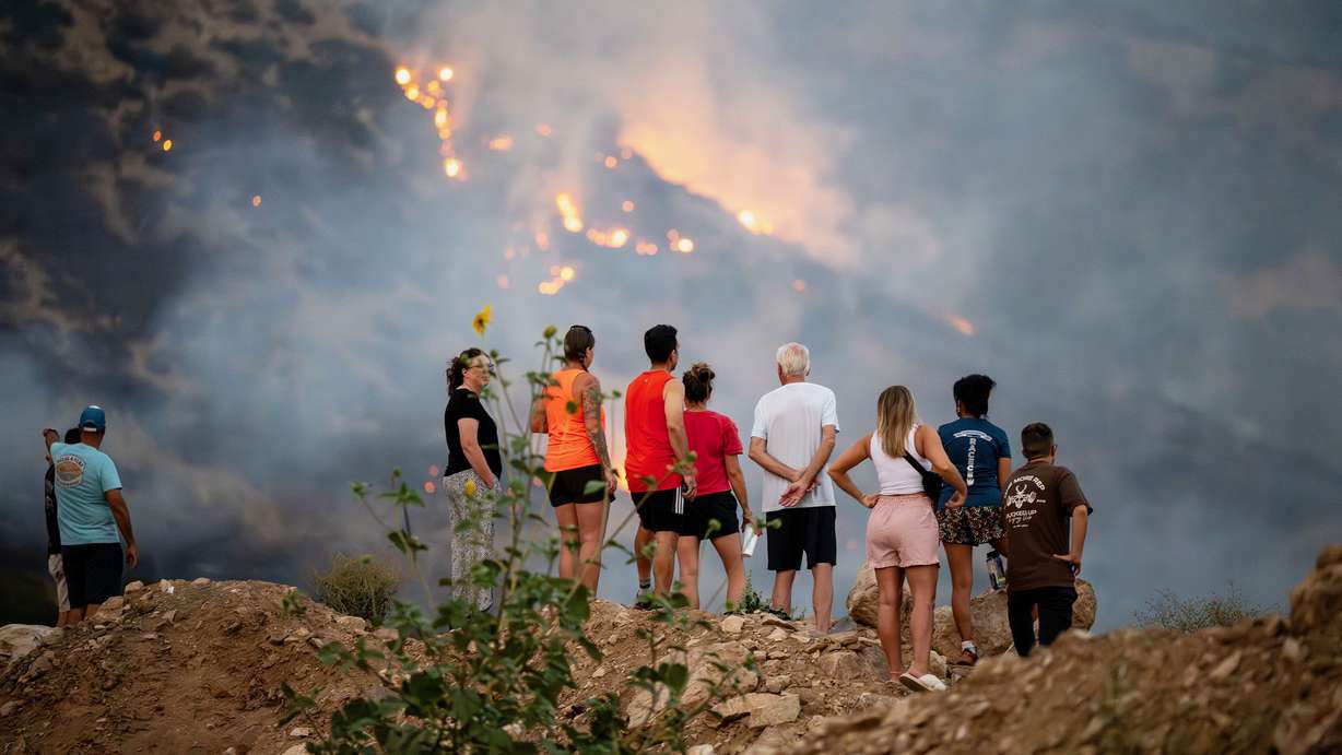 Residents stand on a pushed-up pile of dirt for a better look at the Willard Peak Fire burning near homes and on the mountain in North Ogden on Wednesday. It continued to burn Thursday.