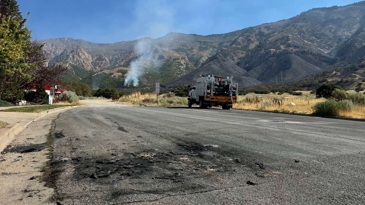 The Willard Peak Fire in North Ogden, pictured Thursday. North View Fire District firefighters were called Wednesday to a burning car near where the blaze started, and black residue from the vehicle fire remained in the street Thursday, visible in the foreground of the picture, though the auto was removed.