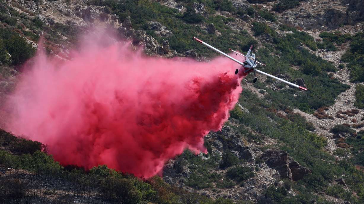 A plane drops fire retardant on the Willard Peak wildfire in the mountains above North Ogden on Thursday.