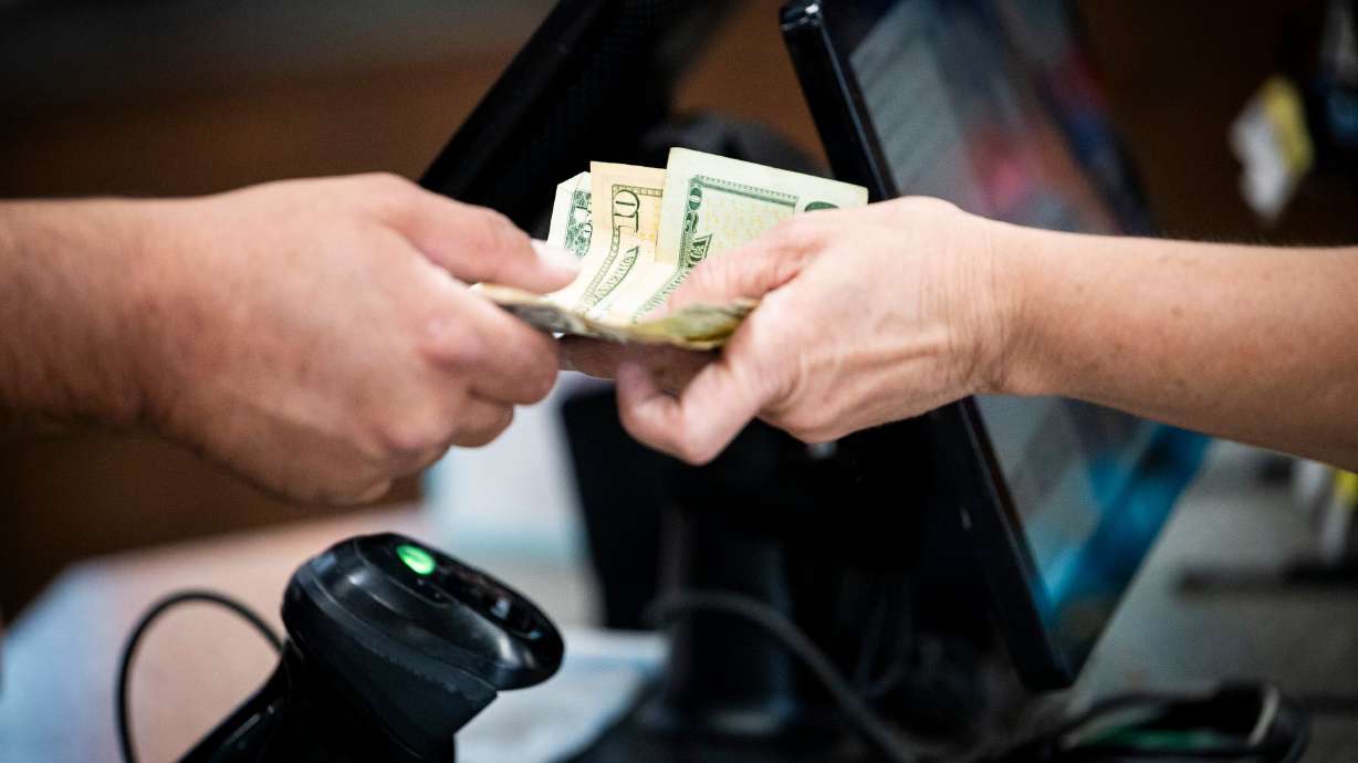 A cashier receives money from a customer at a Maverik in Salt Lake City on June 27. Despite concerns about tariffs and the economy as a whole, a new report shows Utahns are still spending money.