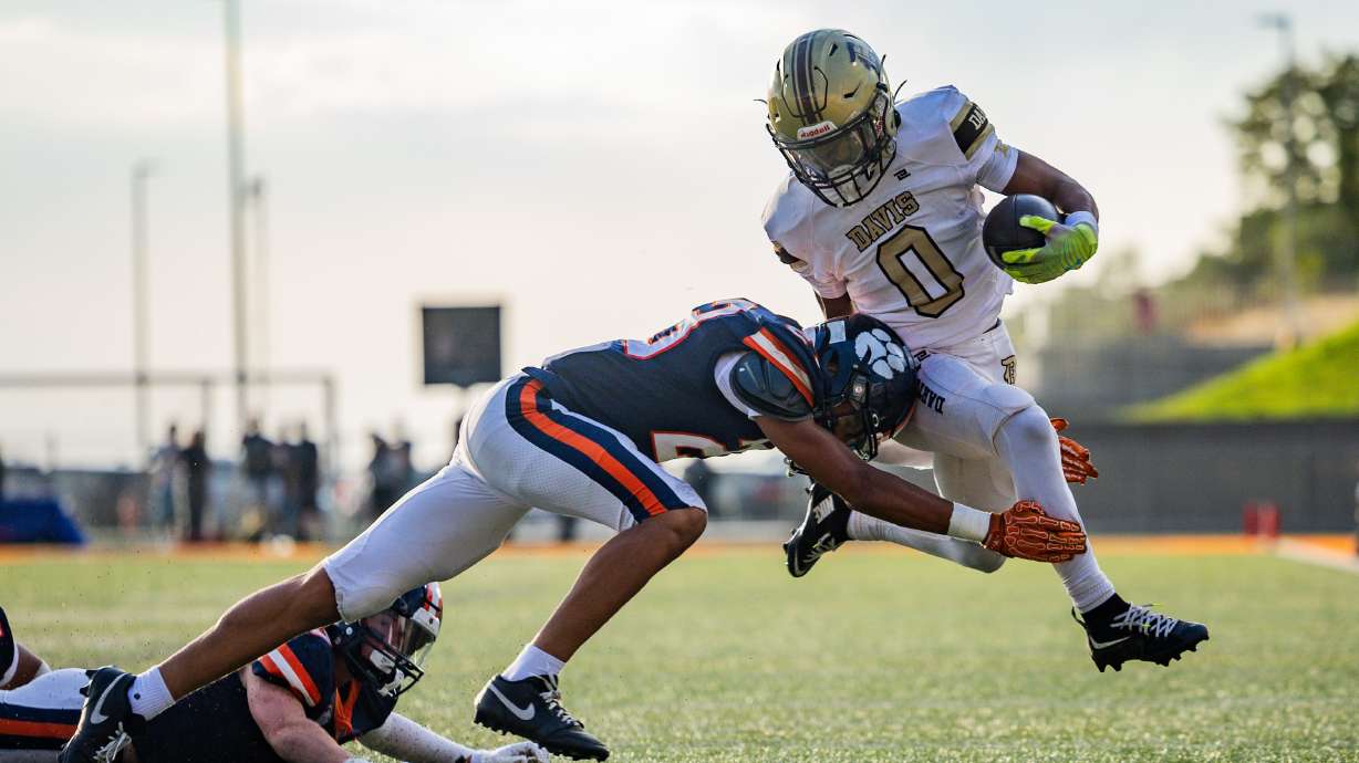 Davis Darts cornerback Makaio Byrd (0) is pulled to the ground by Brighton Bengals cornerback Trey Harper (23) in a football game at Cottonwood Heights on Thursday, Aug. 14, 2025.