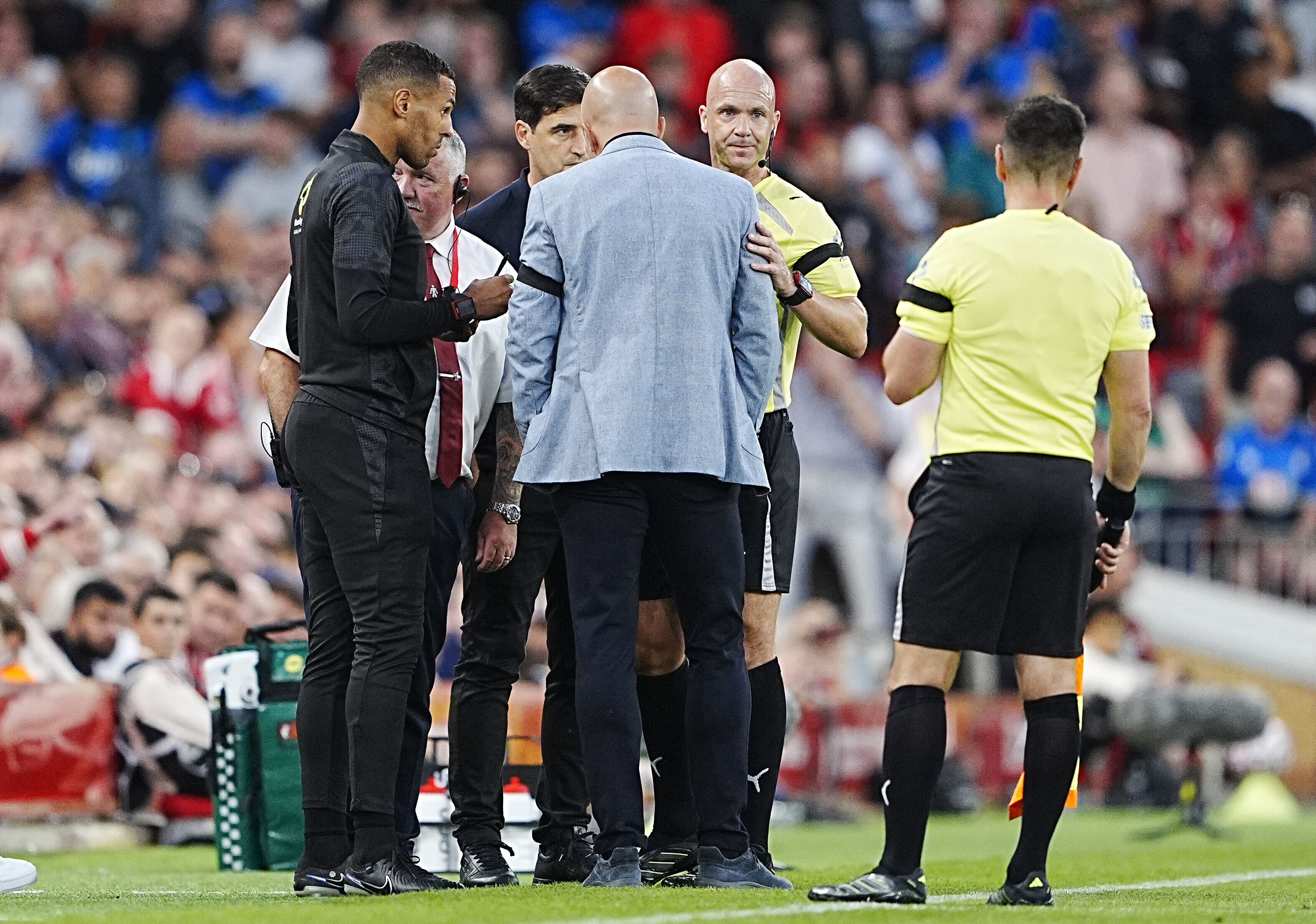 Referee Anthony Taylor speaks with Liverpool manager Arne Slot and Bournemouth manager Andoni Iraola after Bournemouth's Antoine Semenyo, not pictured, informed the referee of a possible racial comment from the crowd during the English Premier League soccer match between Liverpool and Bournemouth at Anfield, Liverpool, England, Friday Aug. 15, 2025.