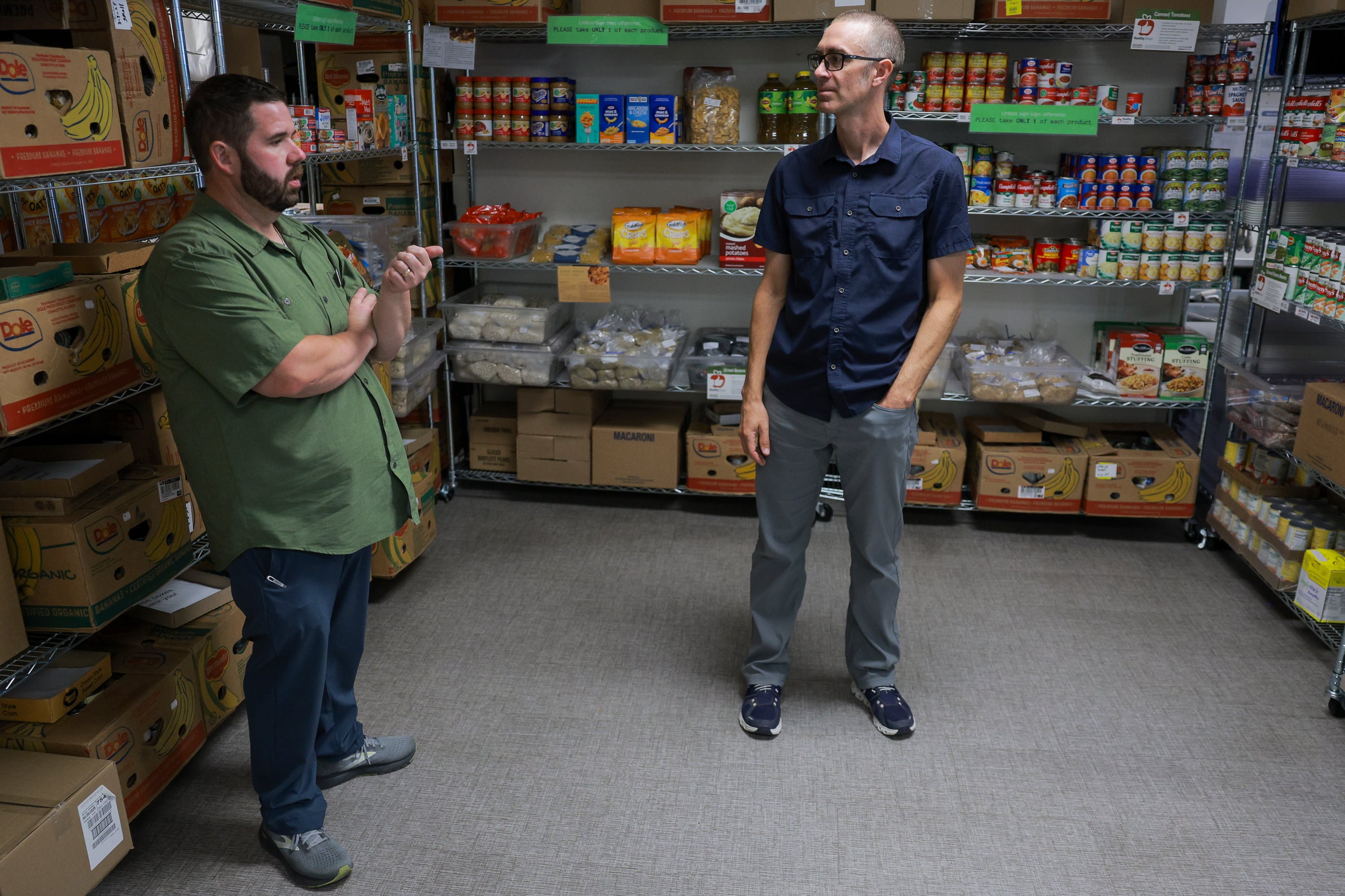 Utah State University Student Nutrition Access Center program coordinator Jonathon Walters, left, and Utah State University psychology professor Michael Twohig, right, talk in the SNAC food pantry at Utah State University in Logan on Aug. 11. Twohig recently donated the money he received from winning a faculty award to the SNAC program.
