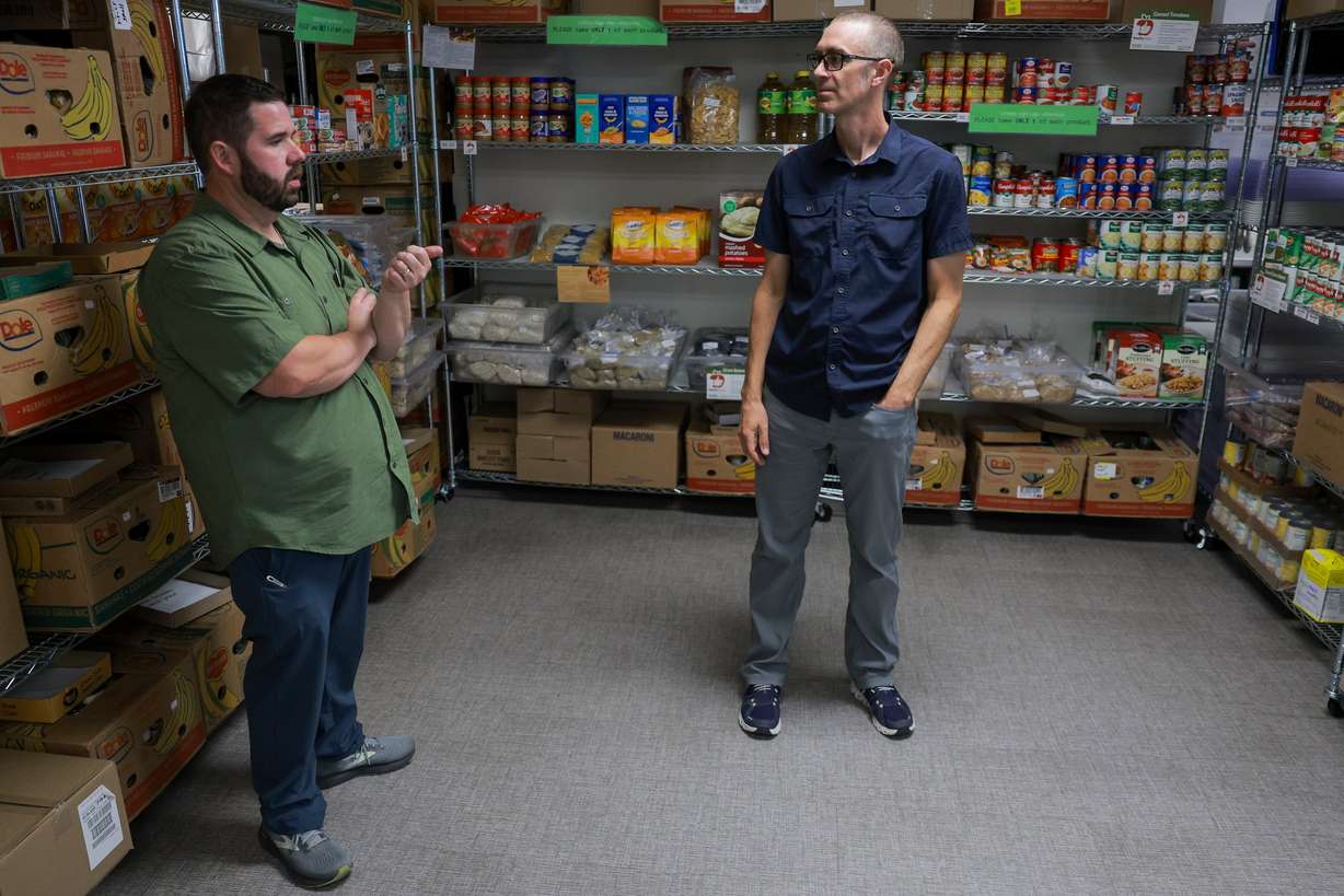 Utah State University Student Nutrition Access Center program coordinator Jonathon Walters, left, and Utah State University psychology professor Michael Twohig, right, talk in the SNAC food pantry at Utah State University in Logan on Aug. 11. Twohig recently donated the money he received from winning a faculty award to the SNAC program.