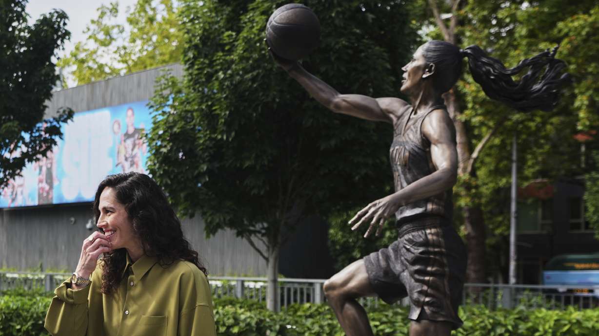 Former Seattle Storm WNBA basketball point guard Sue Bird stands near her statue after its unveiling outside Climate Pledge Arena, Sunday, Aug. 17, 2025, in Seattle.