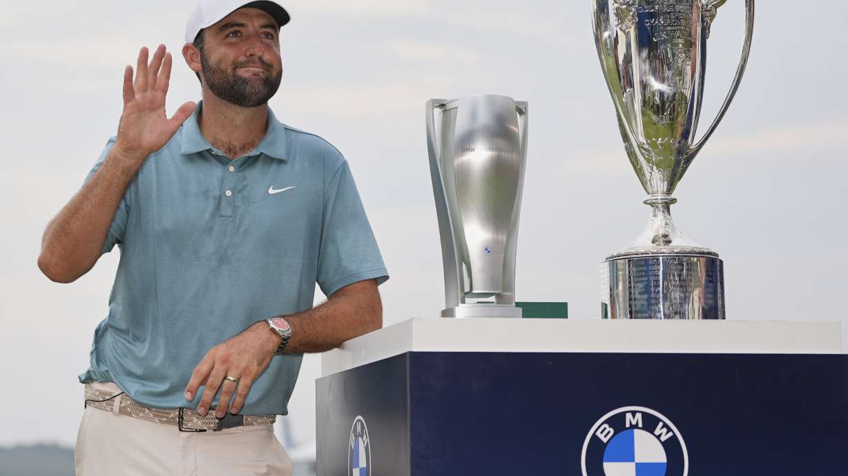 Scottie Scheffler waves while standing with trophies after winning the BMW Championship golf tournament Sunday, Aug. 17, 2025, in Owings Mills, Md.