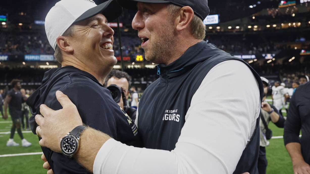 New Orleans Saints head coach Kellen Moore, left, greets Jacksonville Jaguars head coach Liam Coen after an NFL preseason football game in New Orleans, Sunday, Aug. 17, 2025.