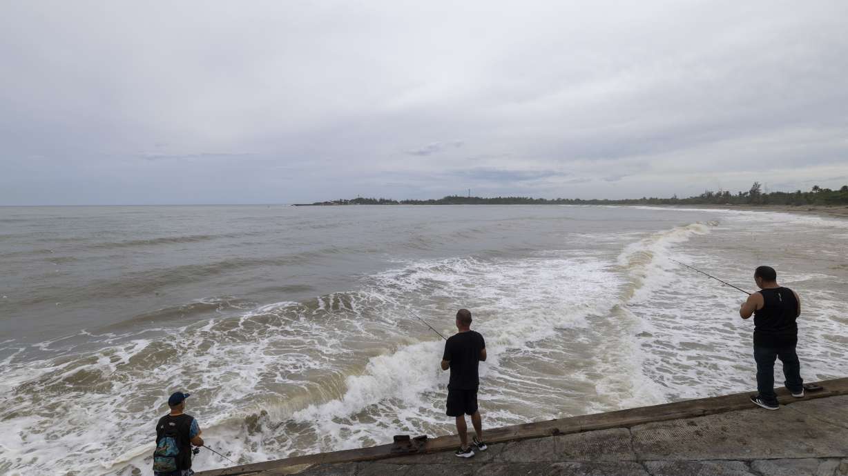 People fish along the shore in Arecibo, Puerto Rico, as Hurricane Erin brings rains to the island, Sunday.