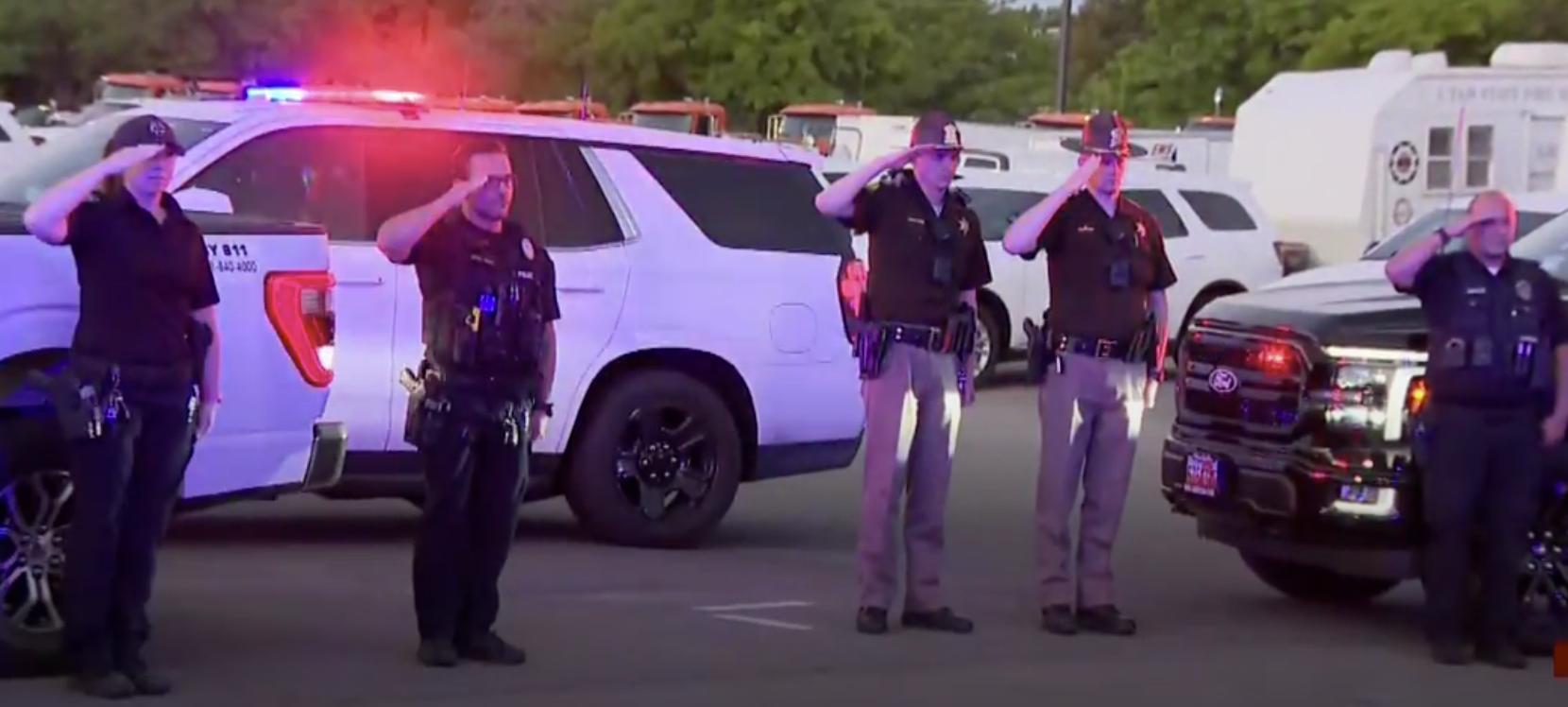 Offices salute as the bodies of two Tremonton police officers are escorted to the Utah Office of the Medical Examiner in Taylorsville on Monday.