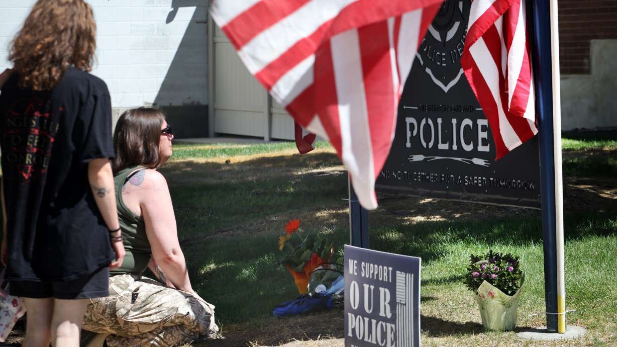 Kristina, who identified herself by her first name only, and two teenagers place flowers on the lawn of the Tremonton-Garland Police Department in memory of two police officers who were shot and killed, in Tremonton, Monday.
