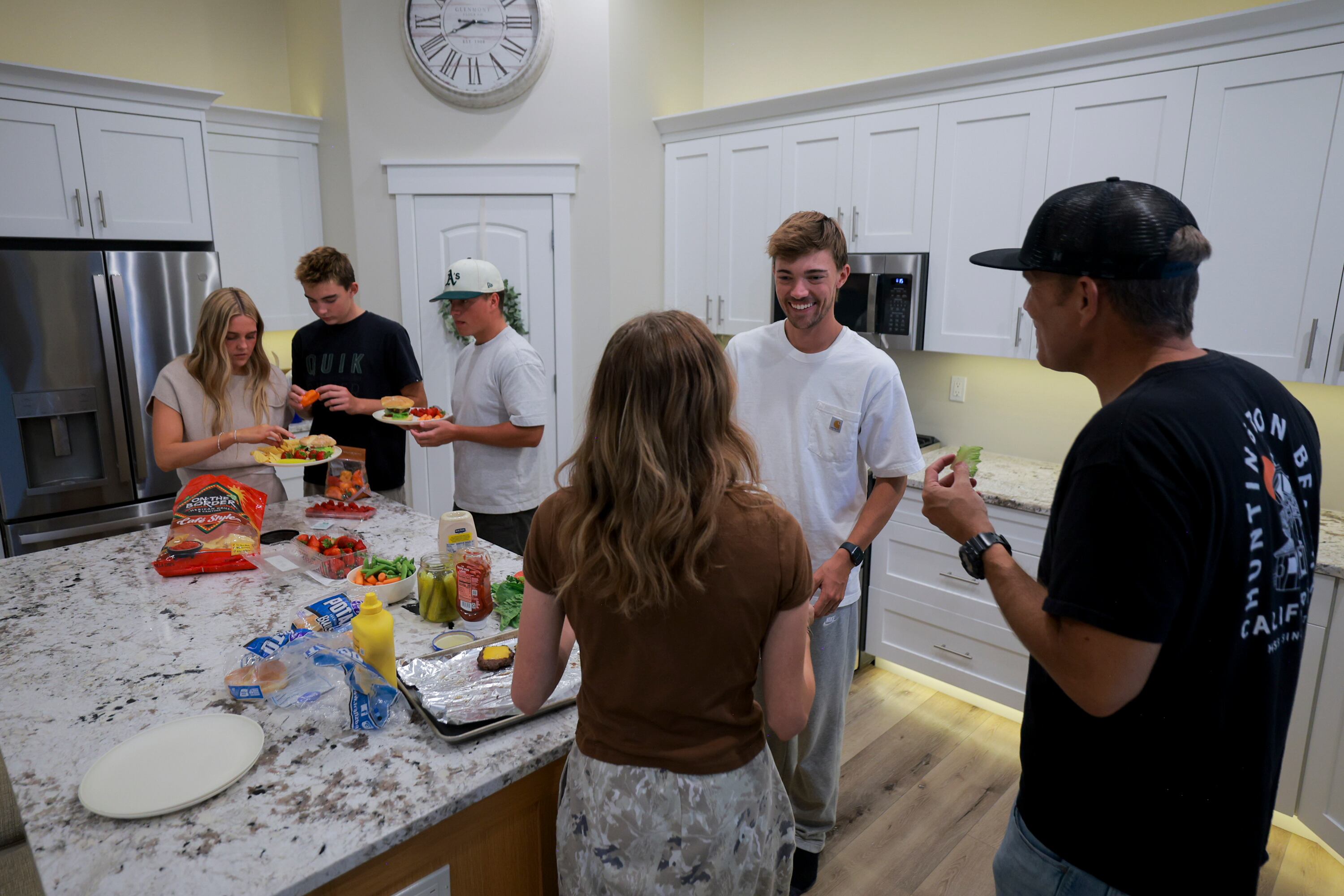 Members of the Olson family make dinner at their home in Layton on Sunday.