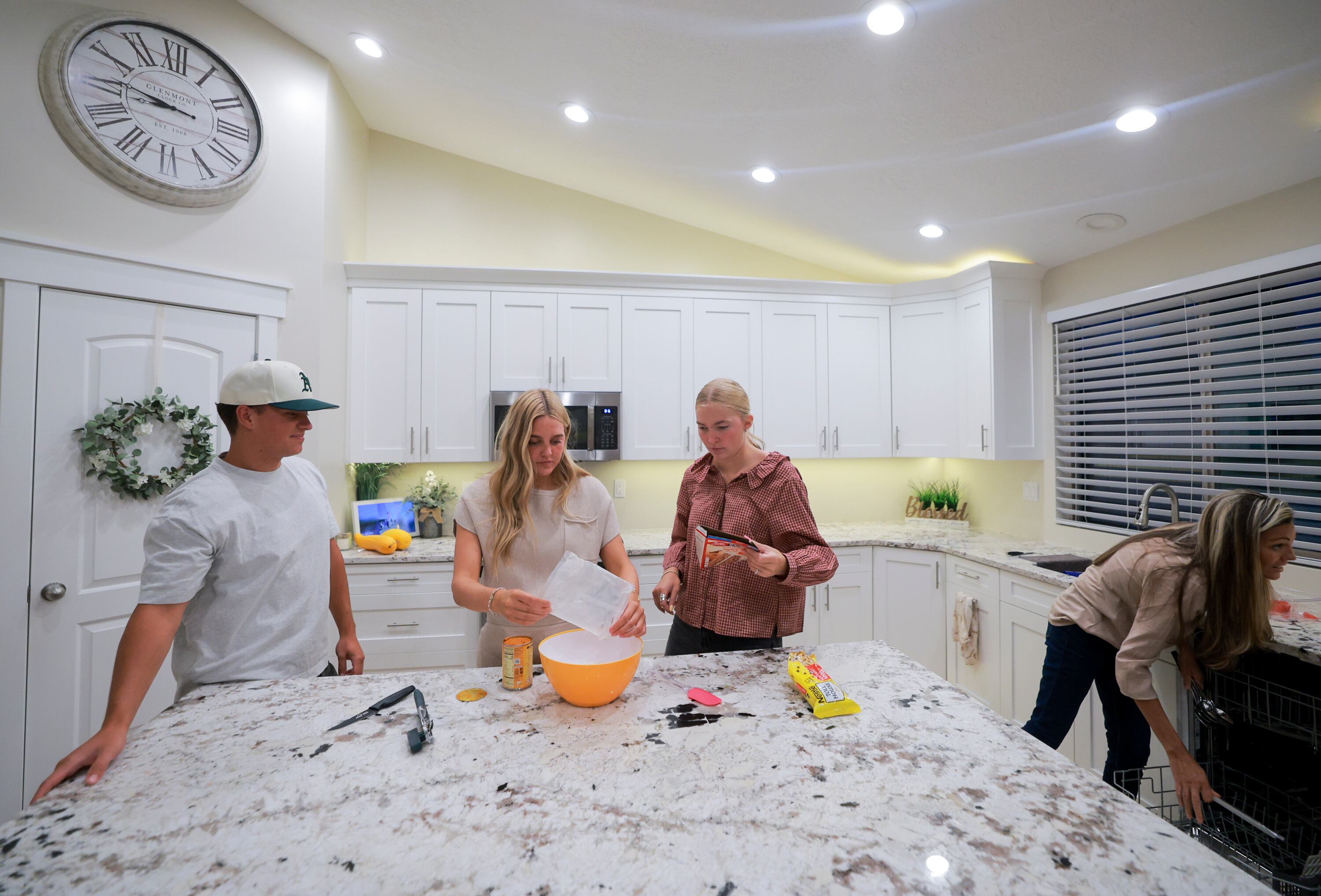 Megan, center left, and Jenna Olson, center right, bake pumpkin cookies with Megan’s boyfriend, Azure Wilson, at the Olson’s home in Layton on Sunday.