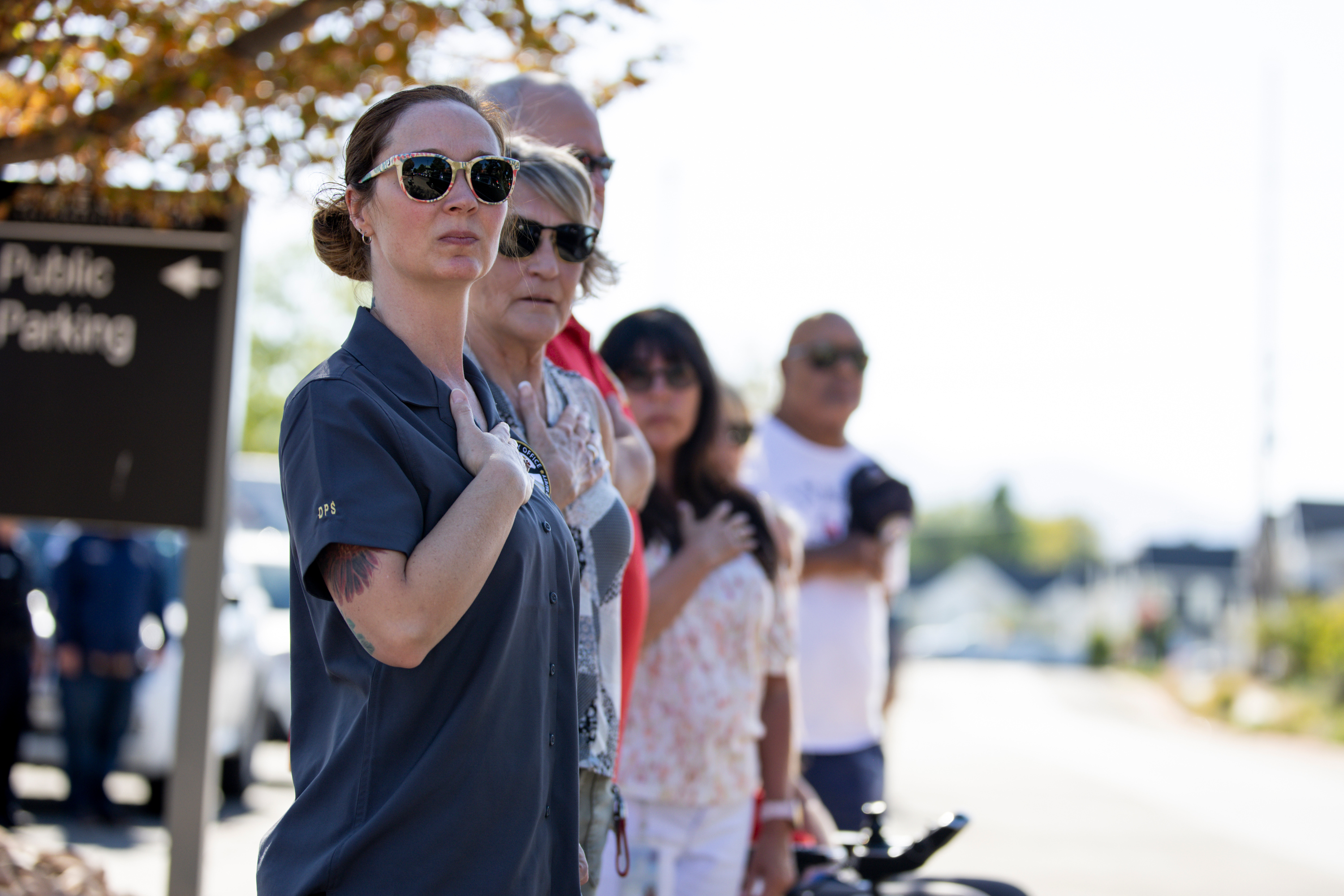 Community members place their hands over their hearts as the hearses carrying the bodies of fallen Trenmont-Garland police officers, Sgt. Lee Sorensen and officer Eric Estrada, depart the Utah State Medical Examiner's Office in Taylorsville to Garland and Logan on Monday.