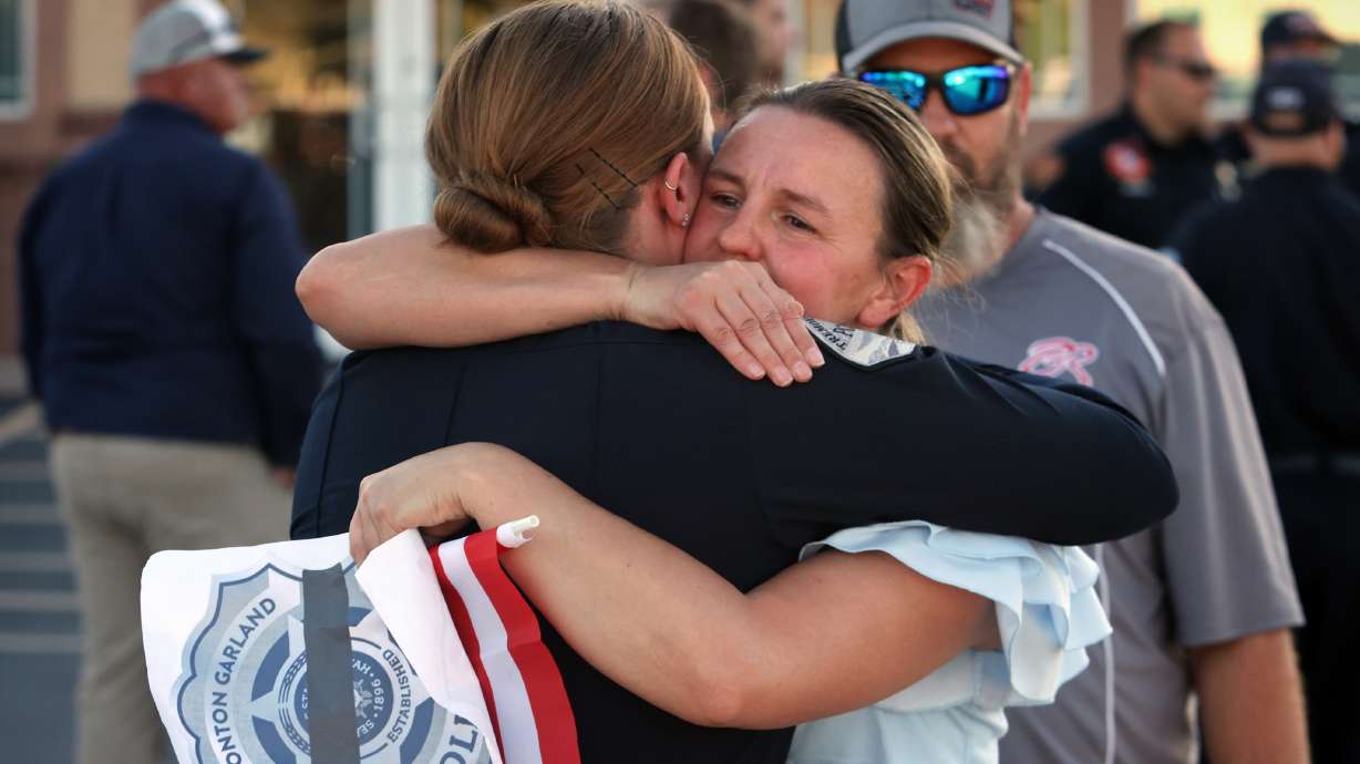 Office Bourne of the Tremonton-Garland Police Department is embraced by supporters after escorting the casket of Sgt. Lee Sorensen is taken to a funeral home on Main Street in Garland, Monday.