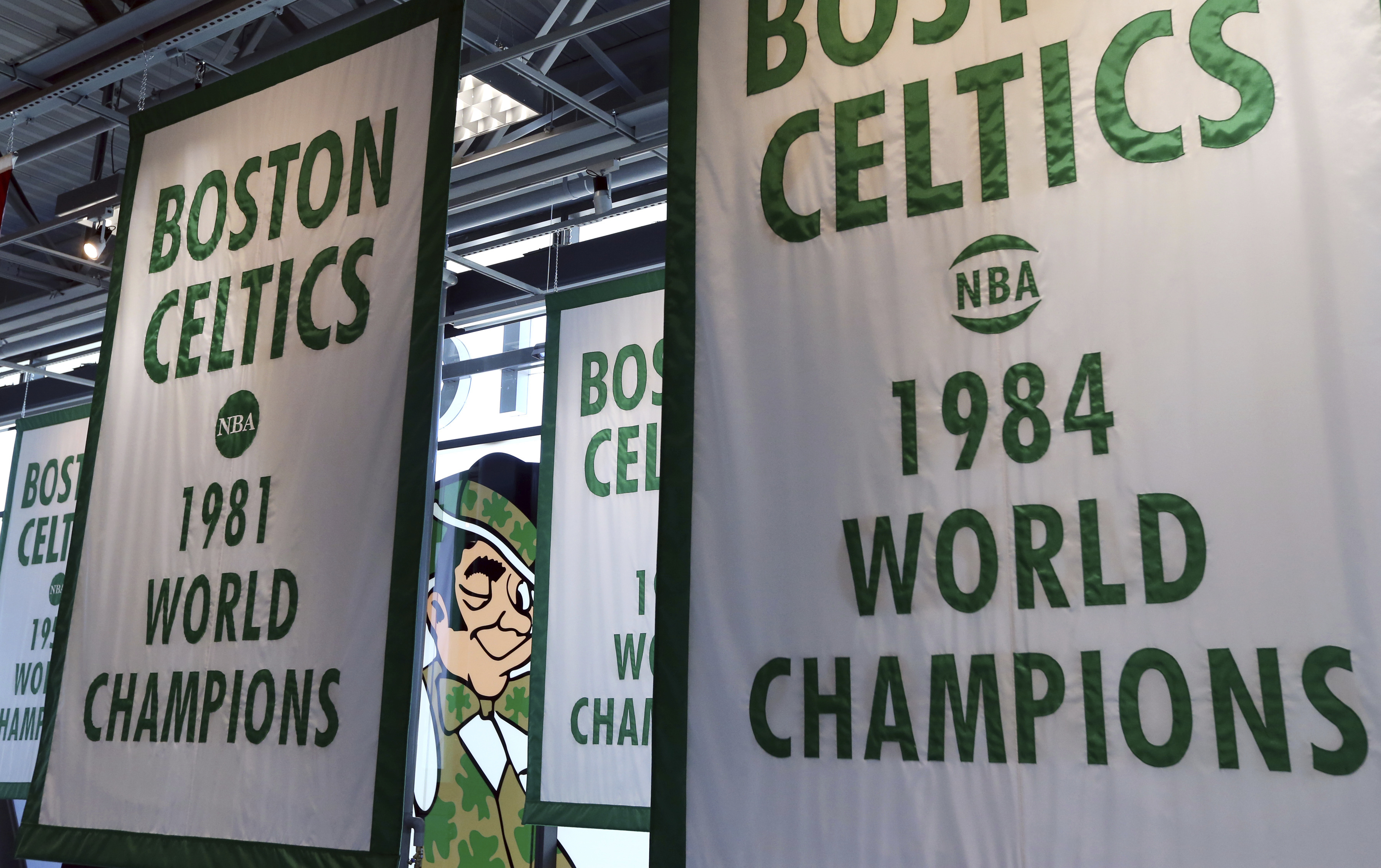 FILE - Lucky the Leprechaun, the Boston Celtics team logo, peers out from in between Celtics championship banners hanging in their new basketball team practice facility, Tuesday, June 19, 2018, in Boston.