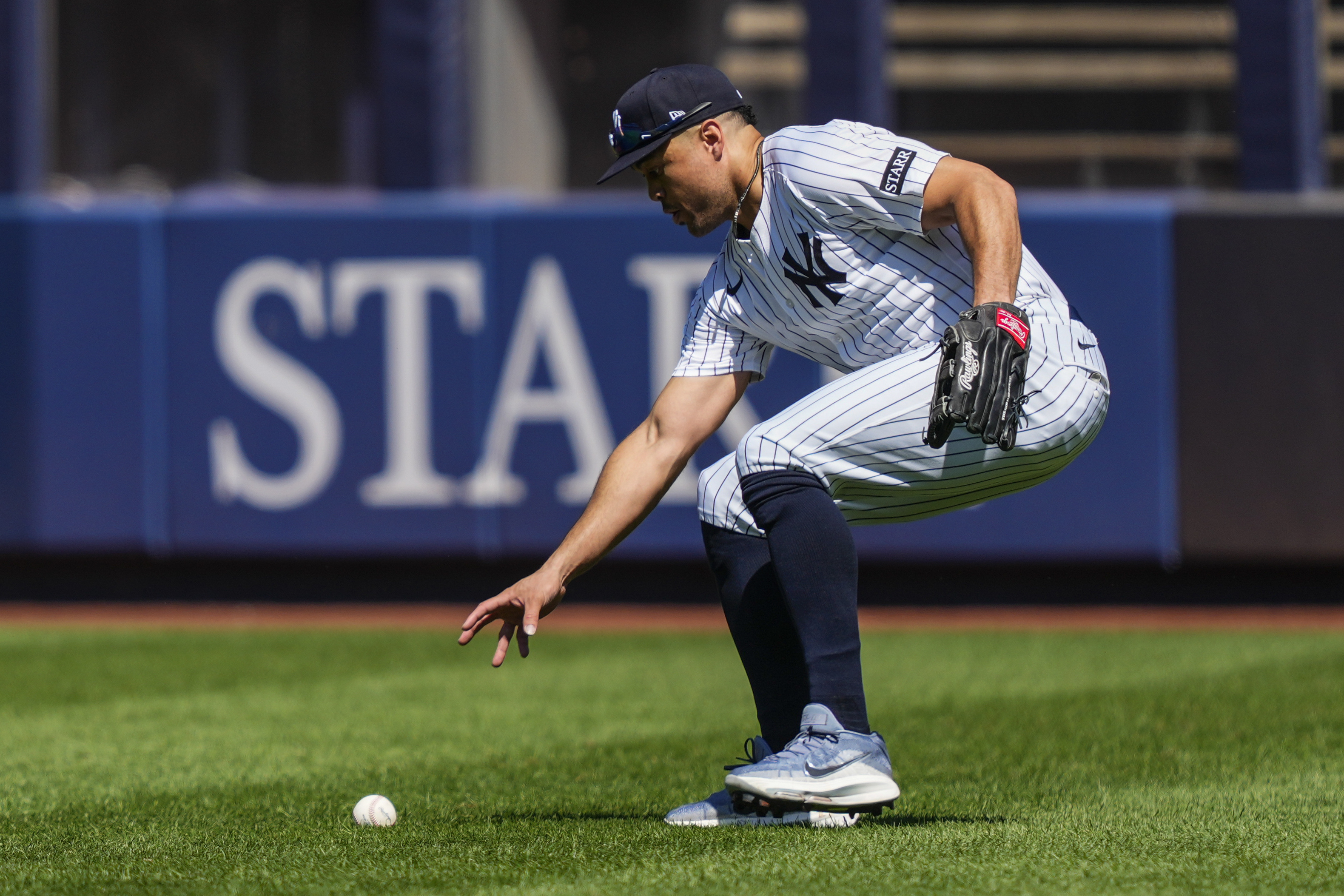 New York Yankees outfielder Giancarlo Stanton picks up a ball hit by Houston Astros' Jesús Sánchez (4) during the fourth inning of a baseball game against the Houston Astros, Saturday, Aug. 9, 2025, in New York. 
