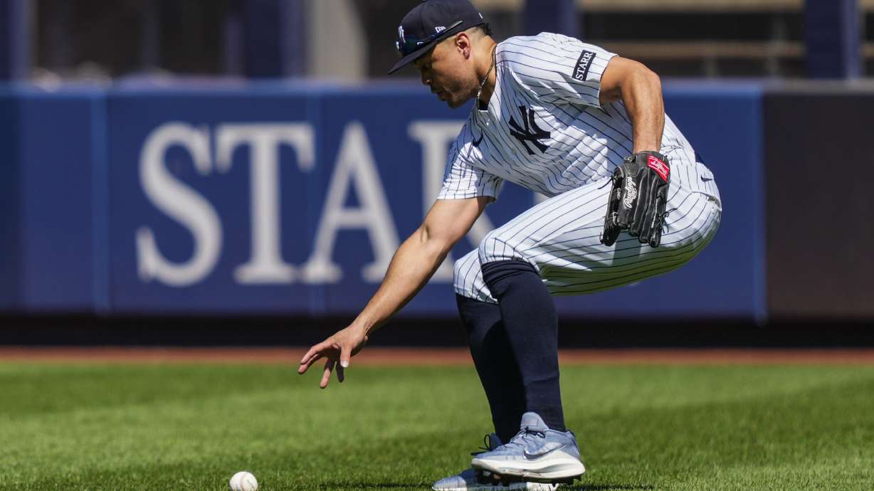 New York Yankees outfielder Giancarlo Stanton picks up a ball hit by Houston Astros' Jesús Sánchez (4) during the fourth inning of a baseball game against the Houston Astros, Saturday, Aug. 9, 2025, in New York.
