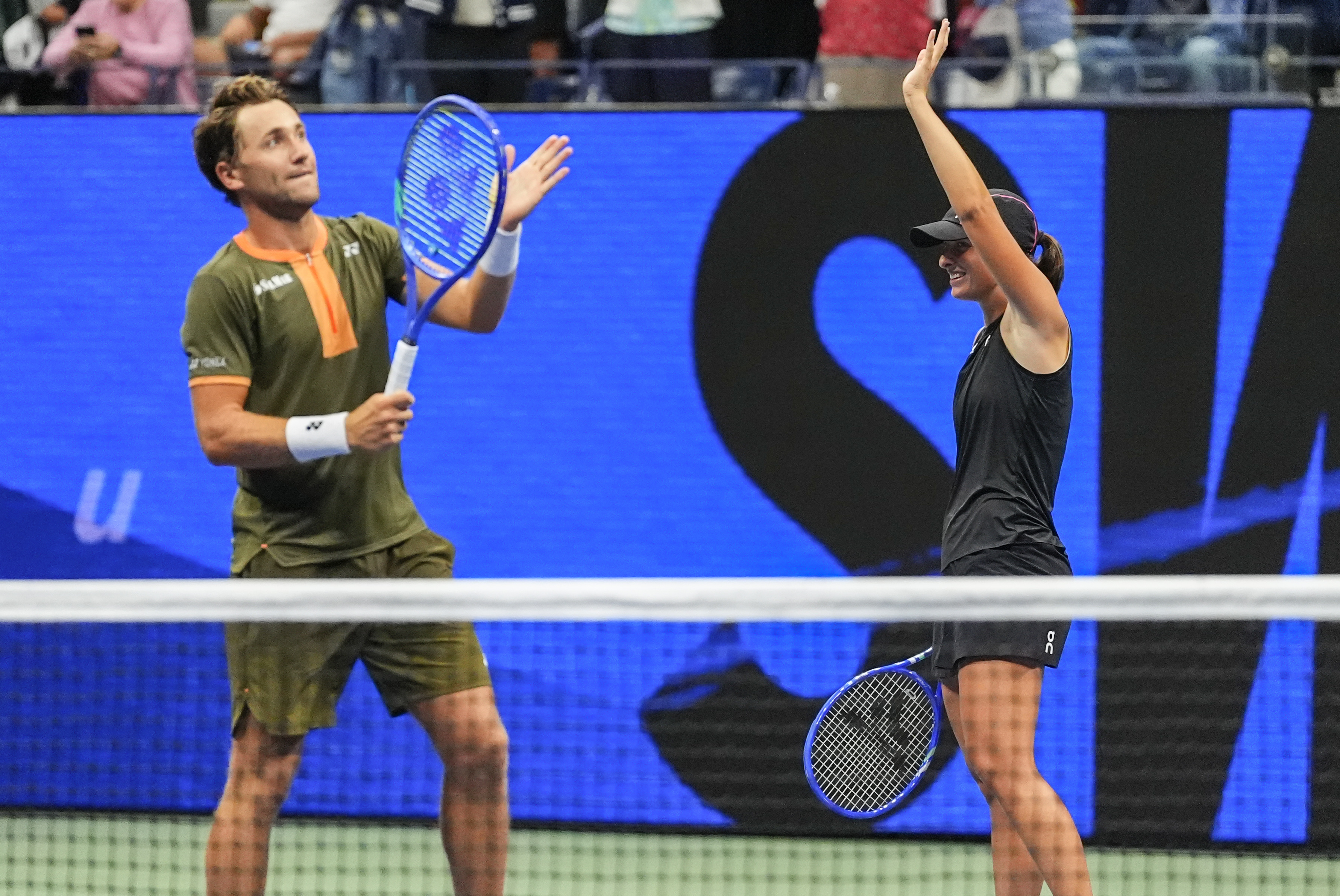 Iga Swiatek, right of Poland, and Casper Ruud, left, of Norway, wave at fans after winning the mixed doubles semi final at the U.S. Open tennis championships, Wednesday, Aug. 20, 2025, in New York.