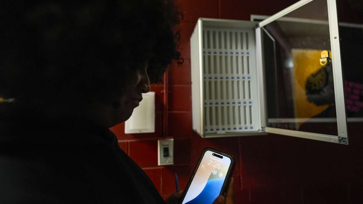 Student Audreanna Johnson views her cellphone near a cellphone locker at Ronald McNair Sr. High School, Aug. 7, in Atlanta. As students start school this year, 17 states and the District of Columbia are imposing new cellphone restrictions.